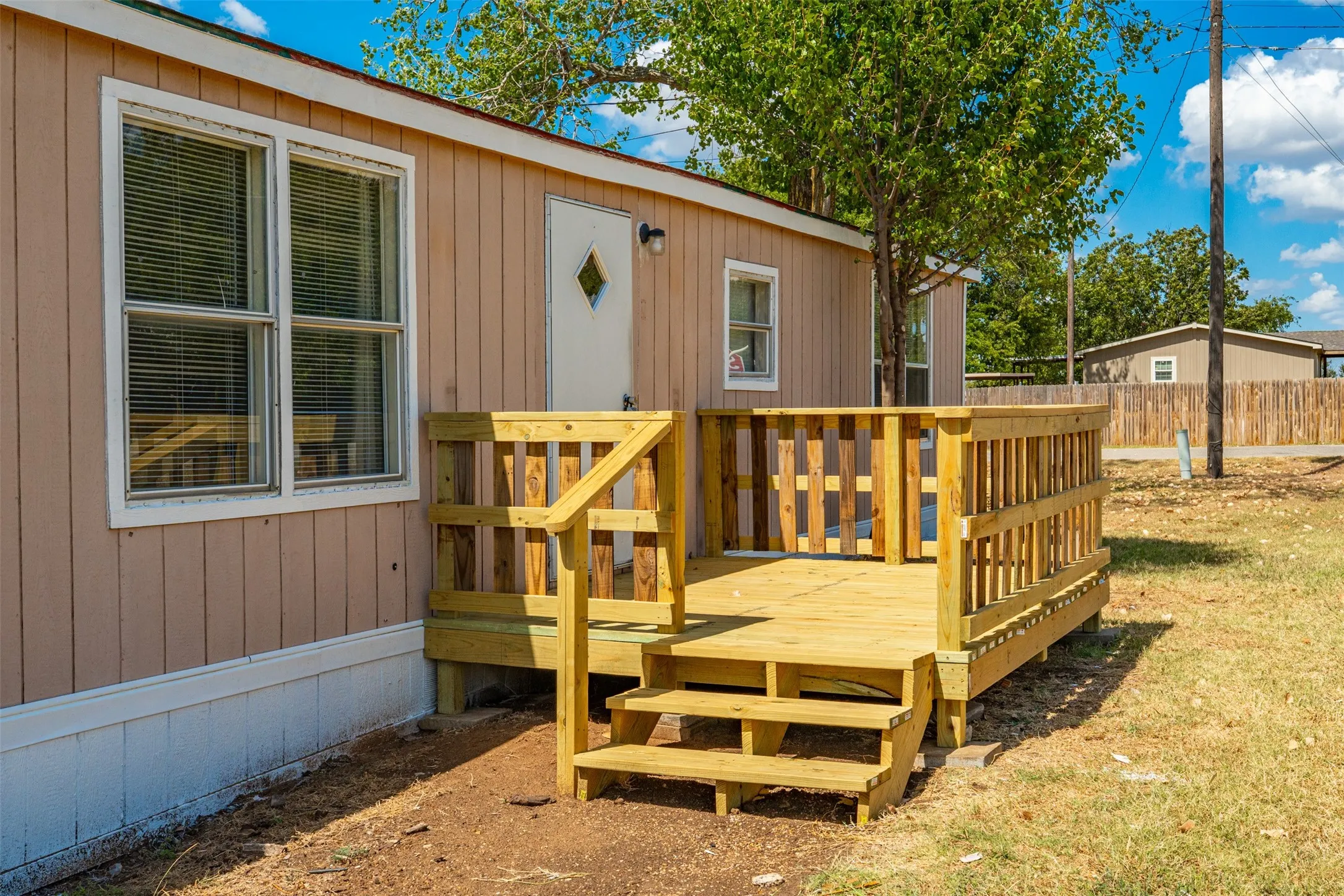 Exterior with vertical panel siding, a wooden deck, and a wood picket railing