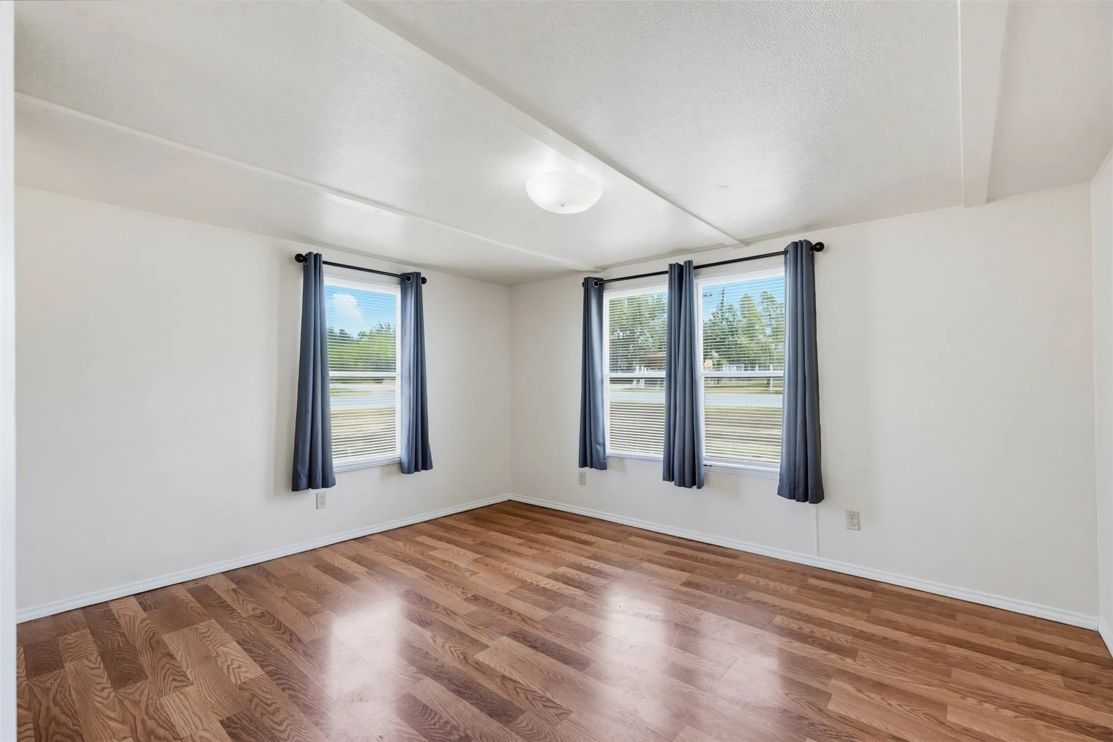 Hardwood-finish flooring, white painted walls, and multiple windows providing natural light
