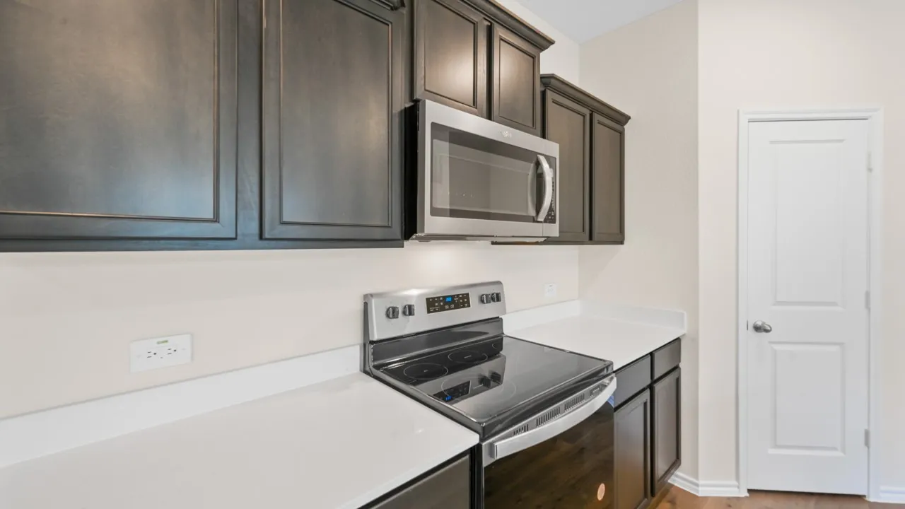 Kitchen featuring dark wood-finish cabinetry, white solid surface countertops, a stainless steel range, and an over-the-range microwave