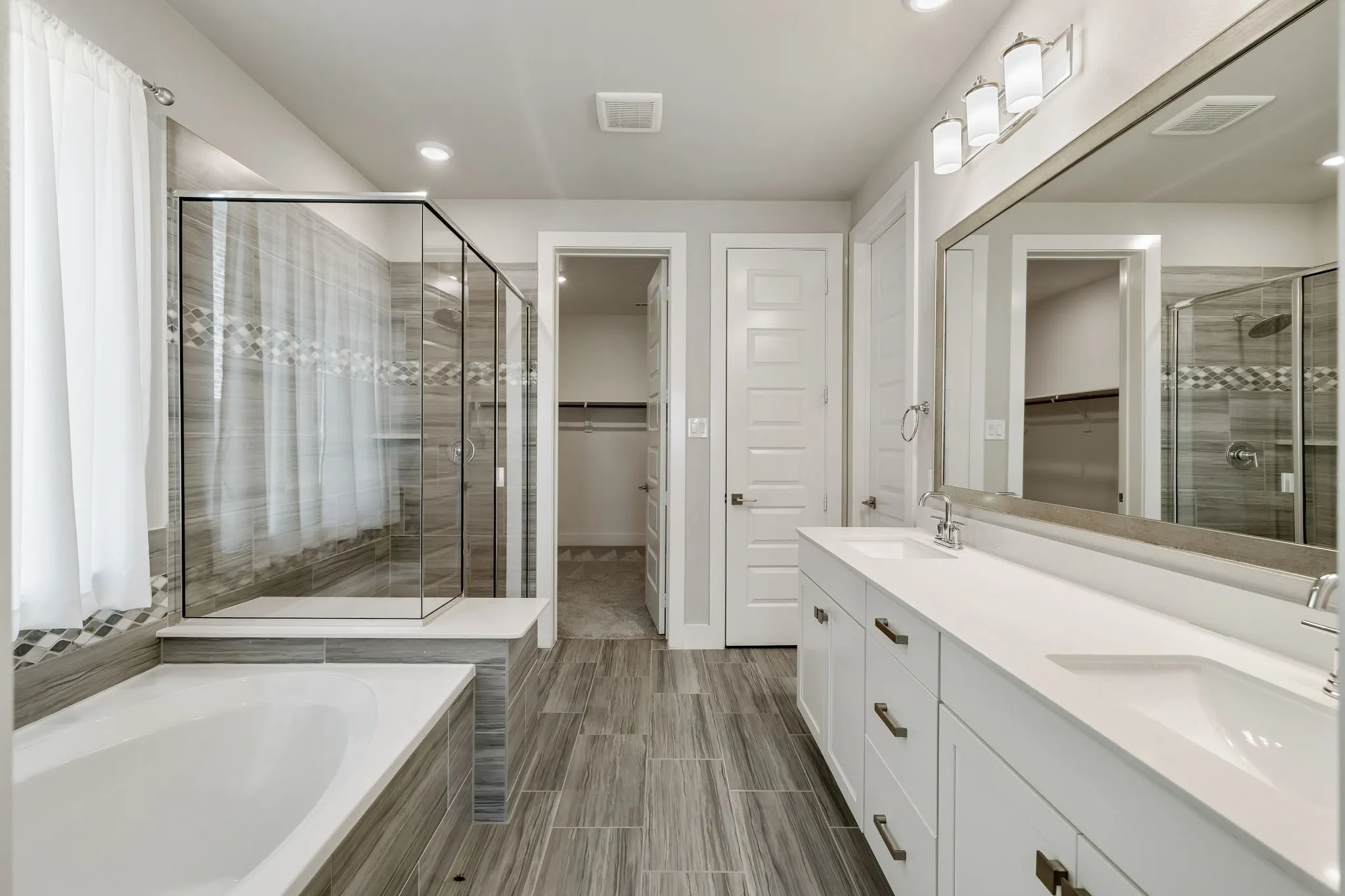 Large vanity with dual integrated sinks, an expansive mirror, and a three-light fixture