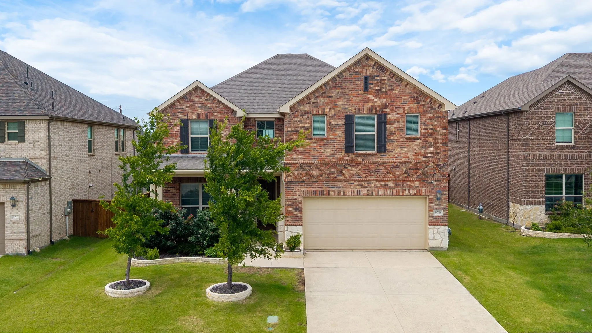 Brick and stone facade residence with a two-car garage and a concrete driveway