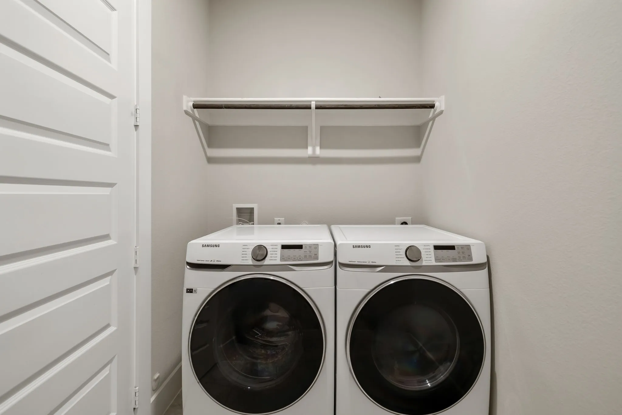 Laundry area with overhead shelving and clothes rod