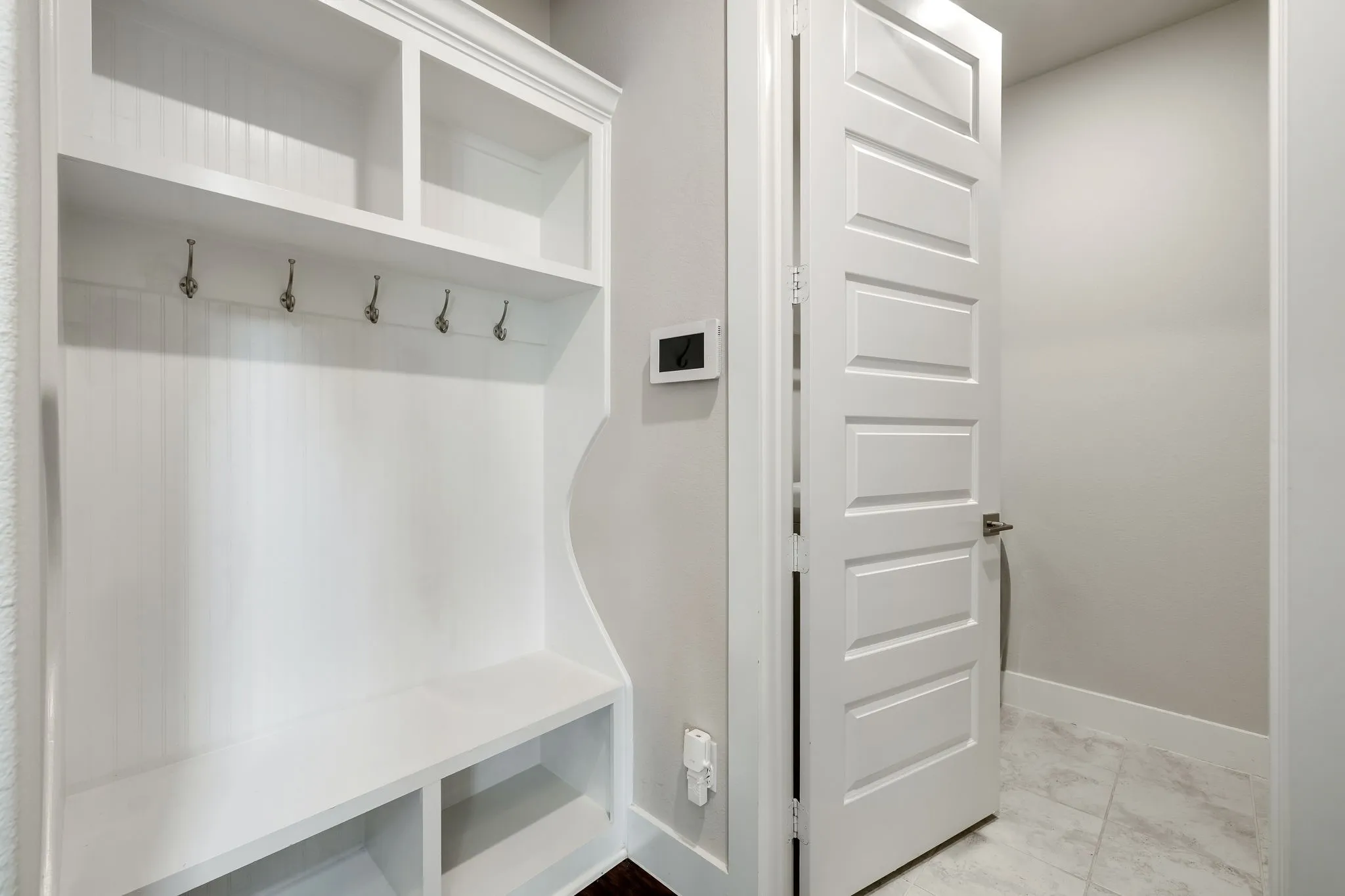 Built-in storage unit with open shelving, integrated bench seating, and wall-mounted hooks