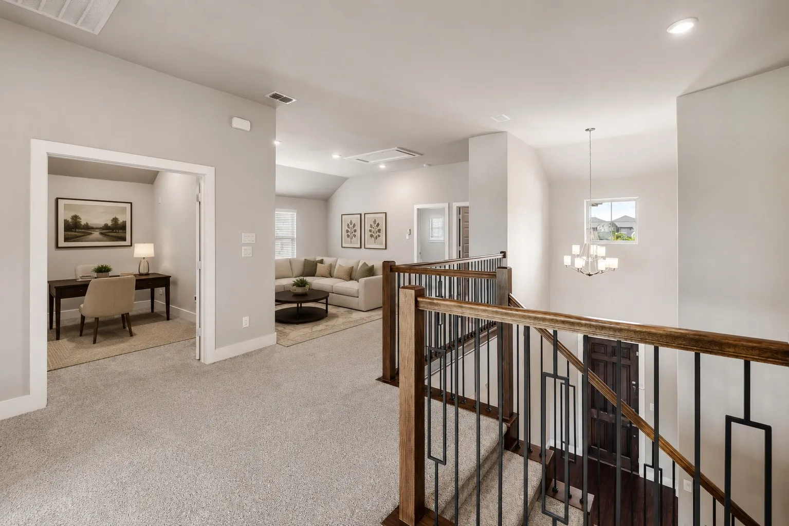 Carpeted flooring throughout, with a wood and wrought iron staircase railing, recessed lighting, and a chandelier fixture