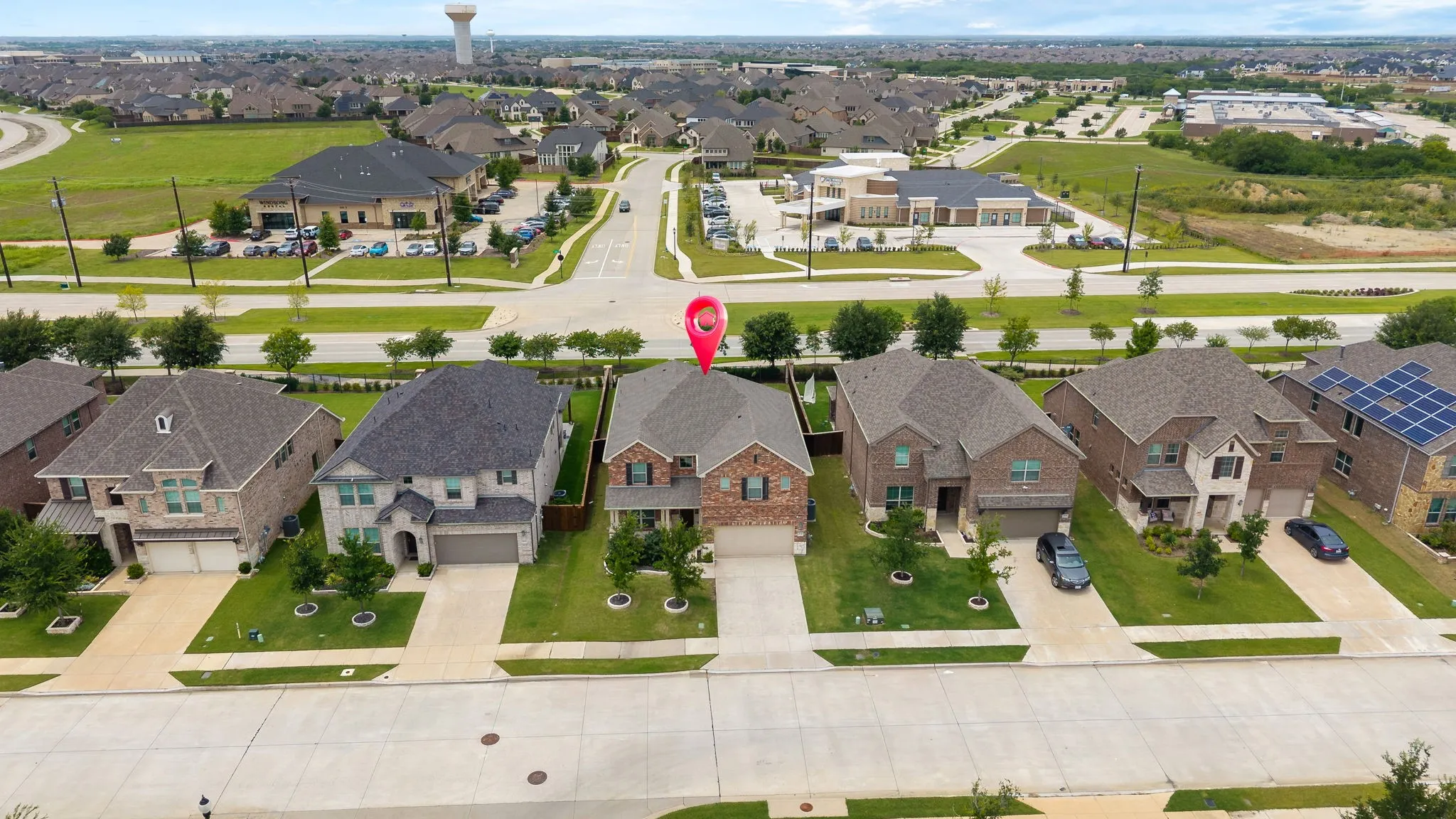 Brick exterior residence with an attached garage, paved driveway, and manicured landscaping