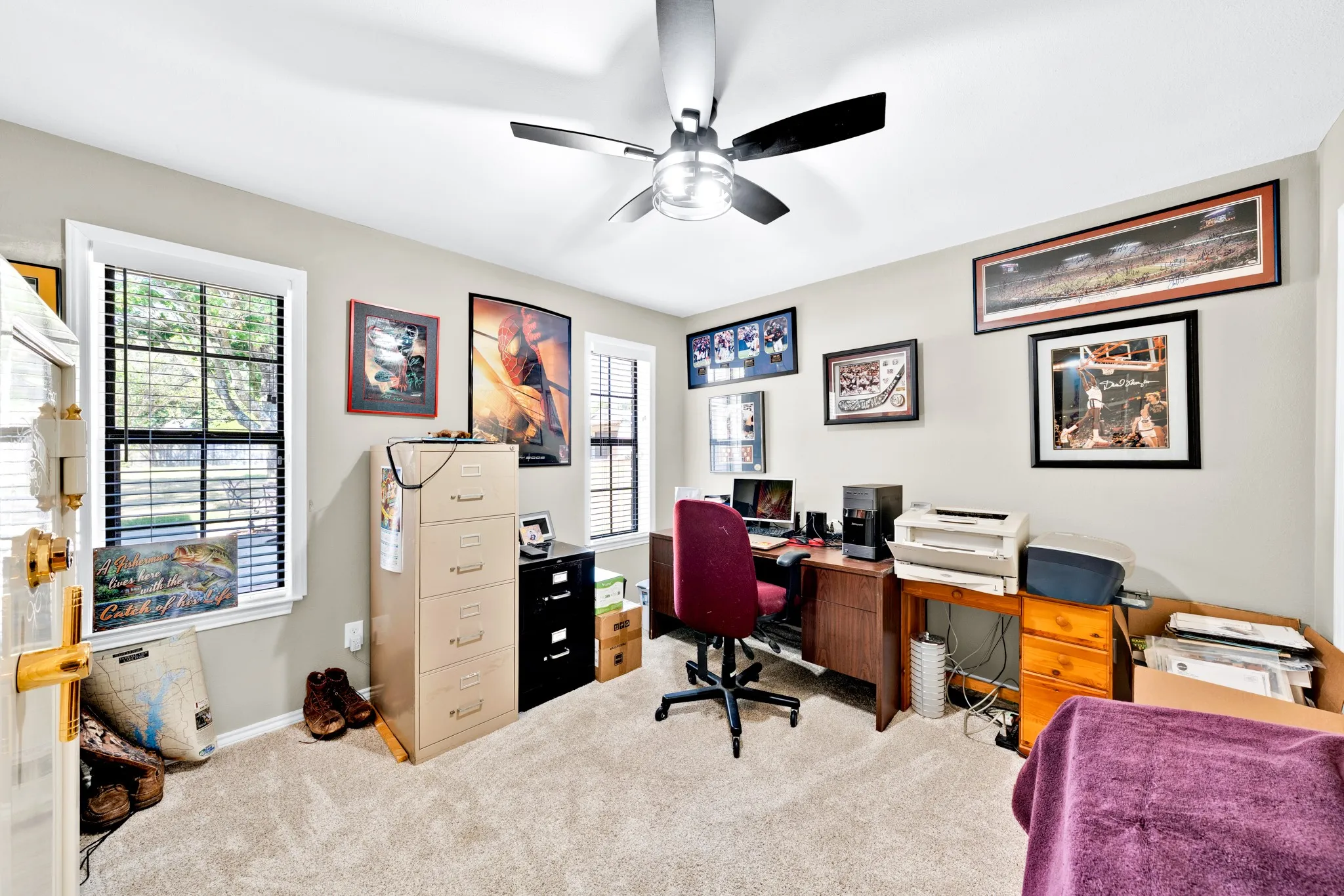Carpeted room featuring multiple windows with blinds, a ceiling fan, and light-toned walls