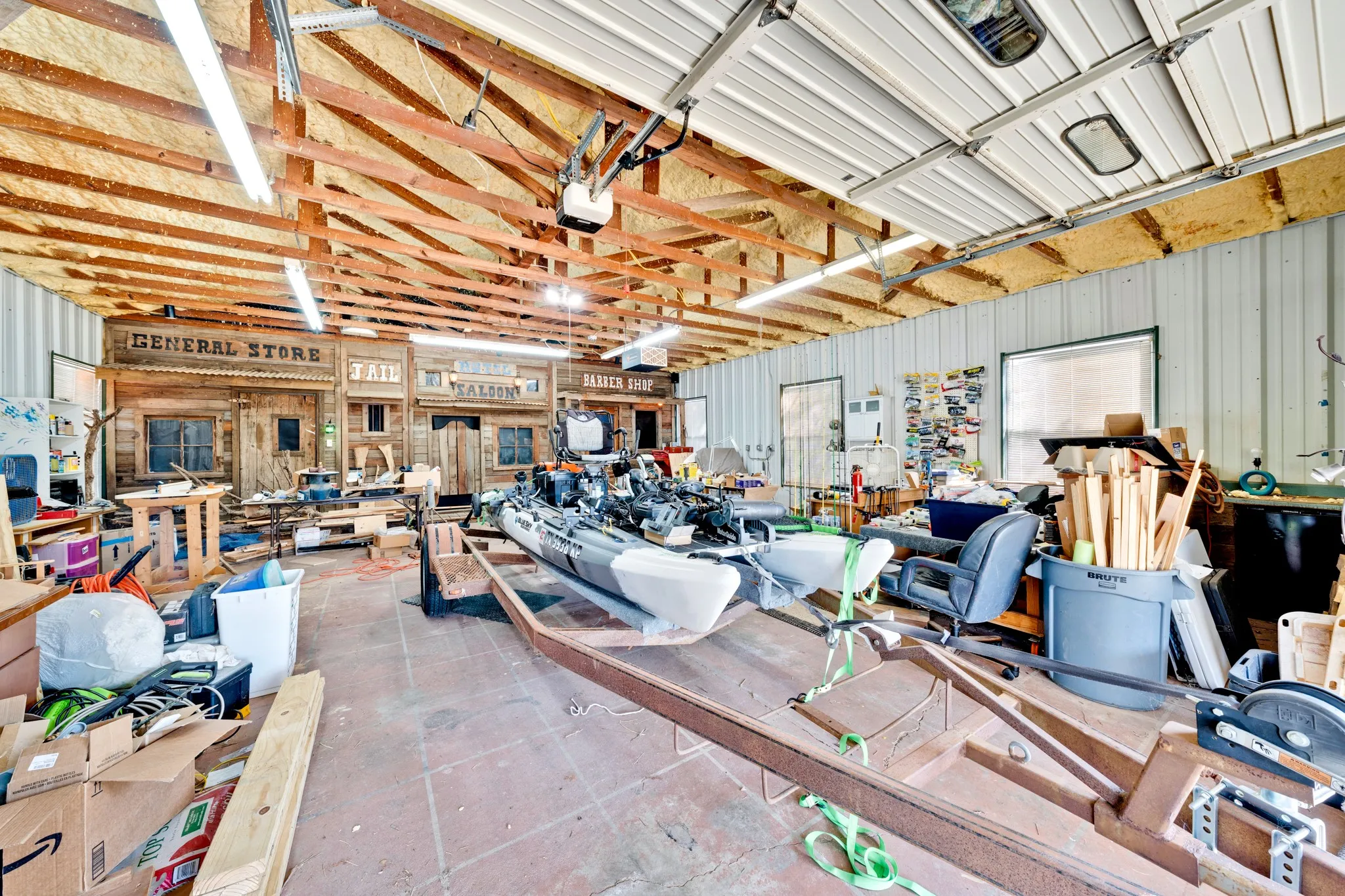 Spacious open interior with exposed wood beams, concrete flooring, and multiple fluorescent light fixtures