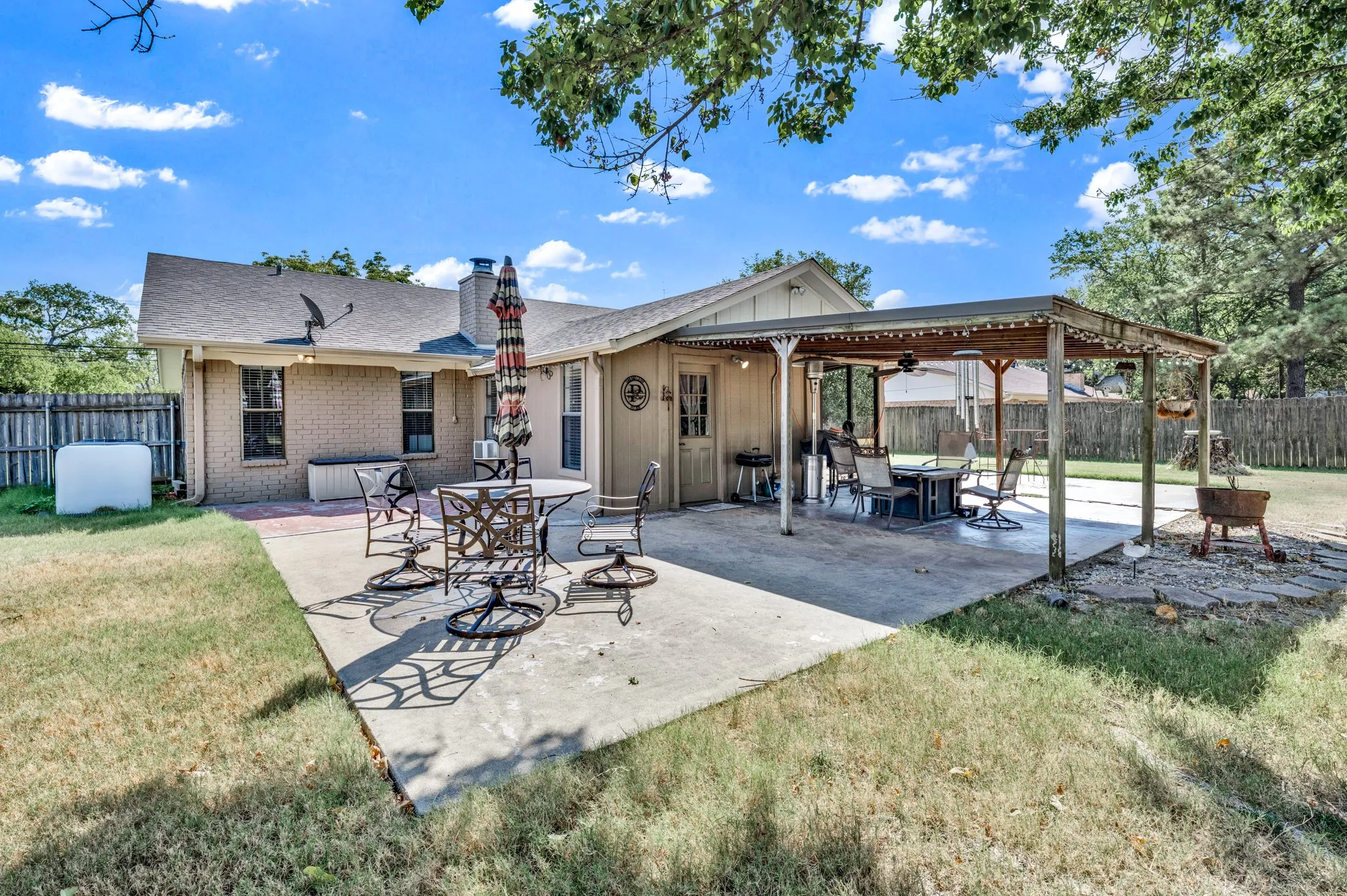 Expansive concrete patio area with a covered wood pergola, offering an additional concrete pad