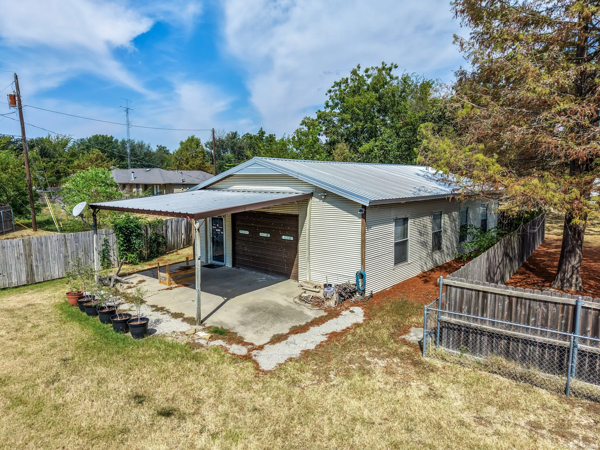 Metal roof, attached carport, horizontal siding, wood fence, and chain-link fence