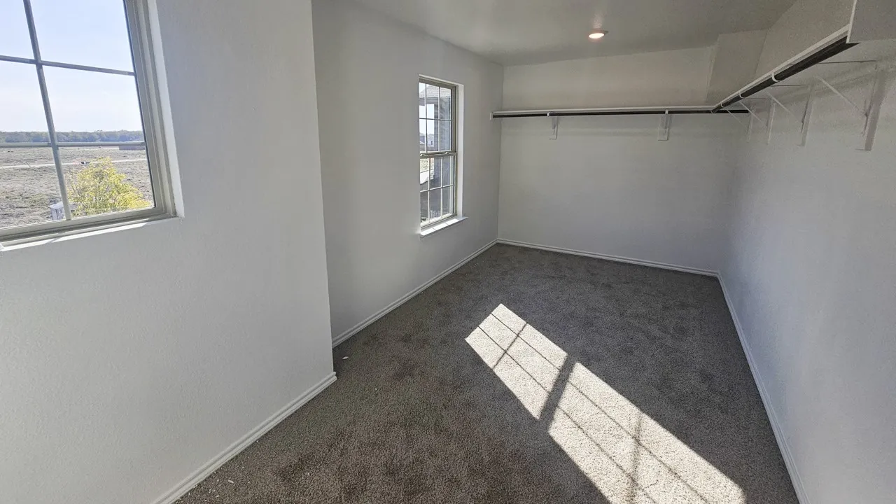 Carpeted room featuring multiple windows, a recessed ceiling light, and built-in closet shelving