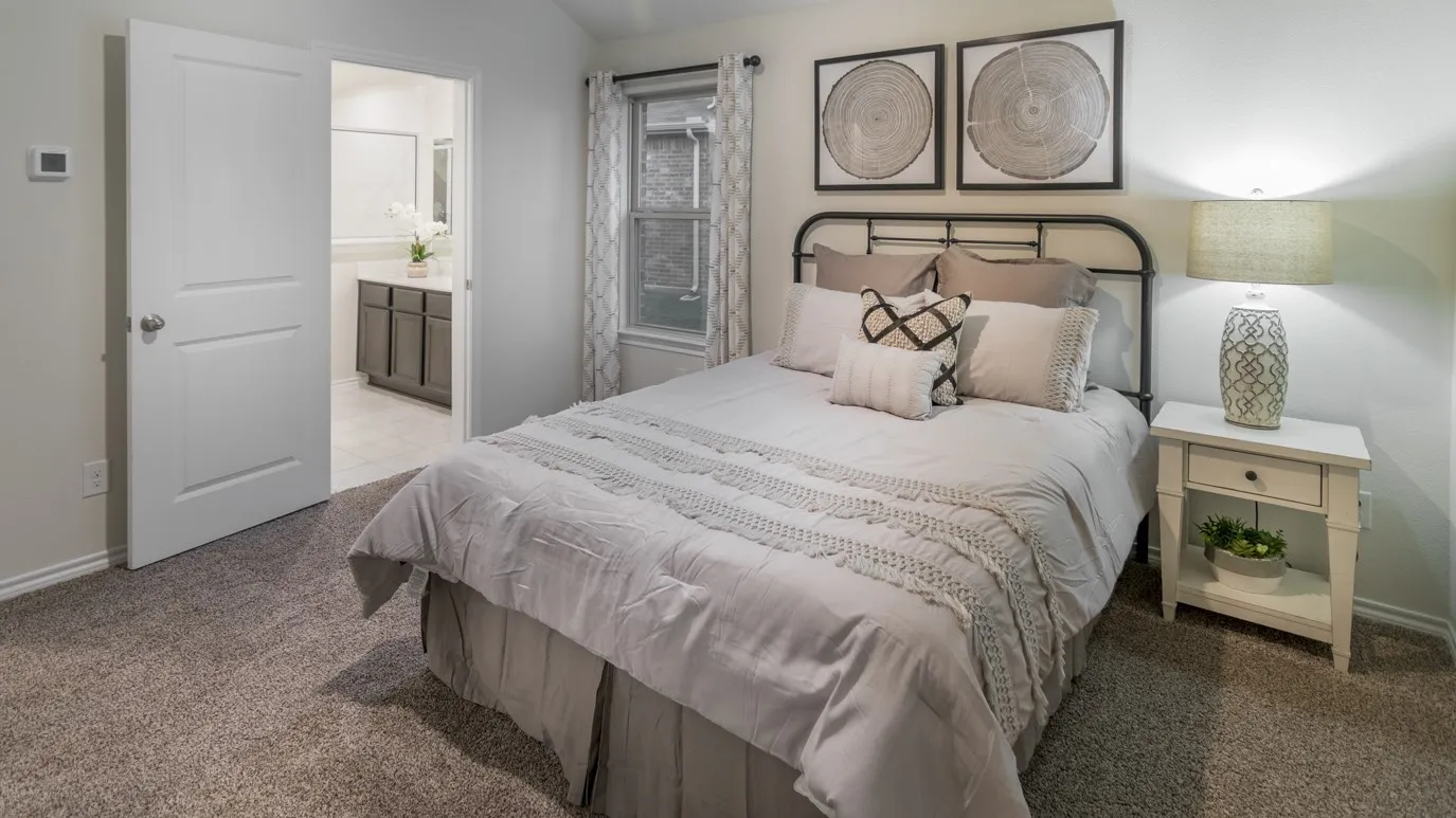 Carpeted bedroom featuring a window with patterned drapes, a white paneled door, and a thermostat