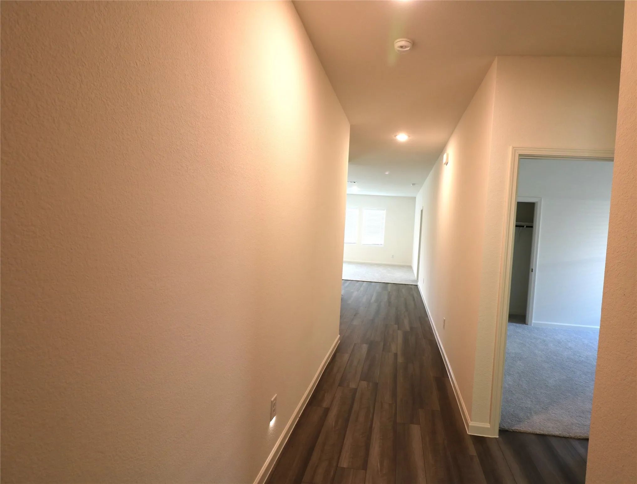 Hallway with wood-finish flooring, recessed lighting, and a neutral color palette