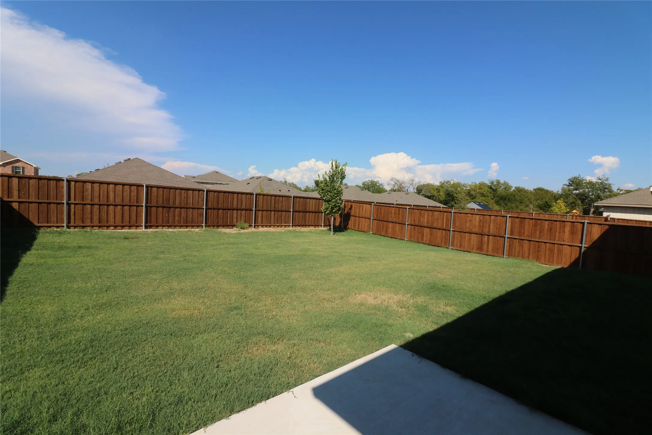 Expansive backyard featuring a manicured lawn, a privacy fence, and a concrete patio