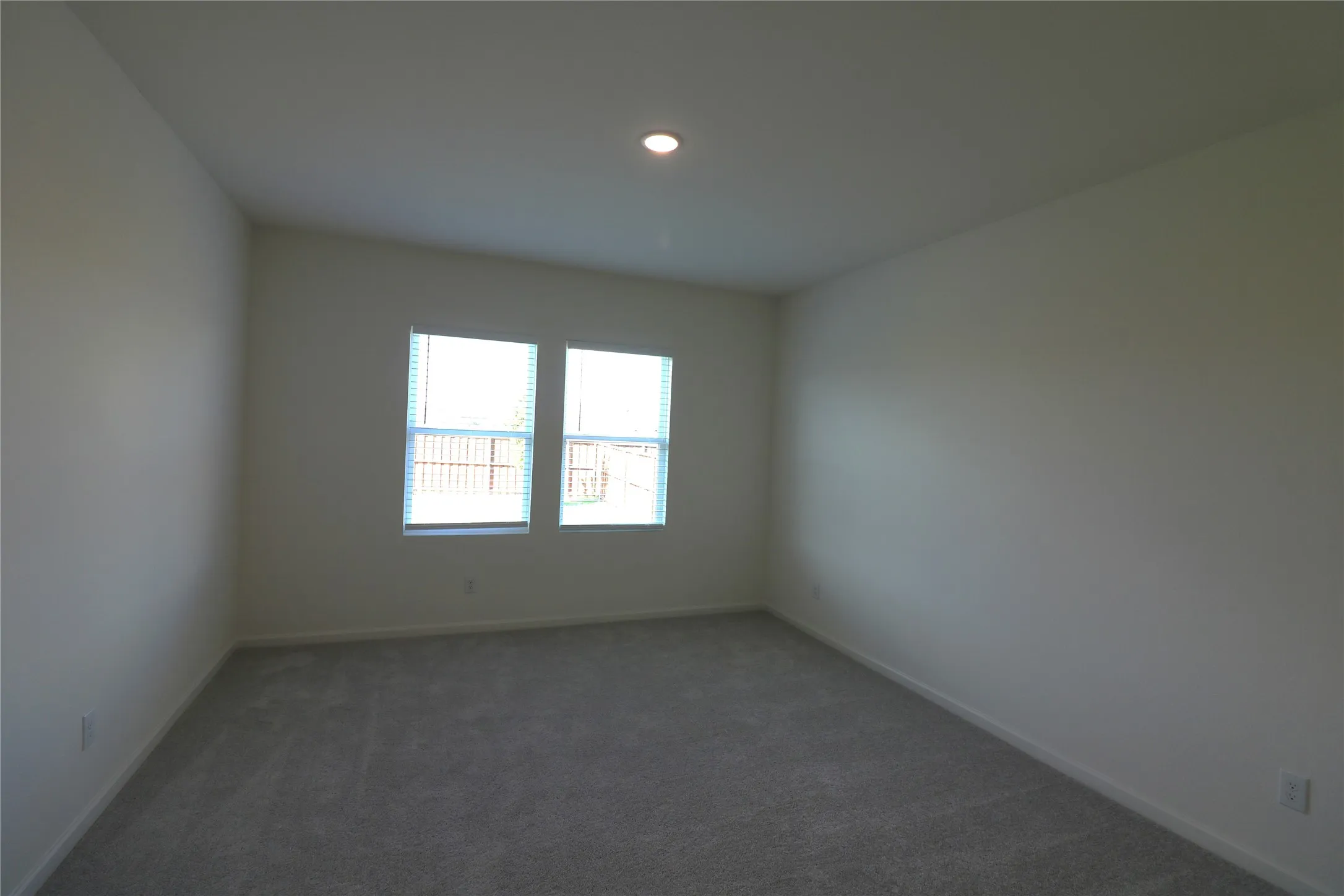 Recessed ceiling lighting, light gray wall paint, light gray carpet, and two double-hung windows