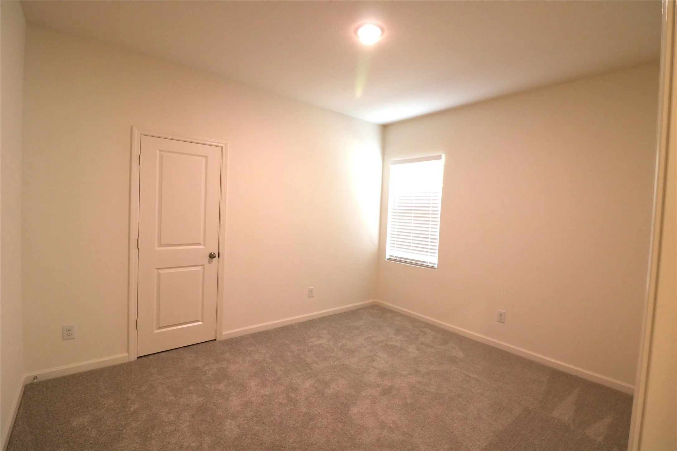 Recessed ceiling light, neutral wall palette, carpeted flooring, window with blinds, and white interior door