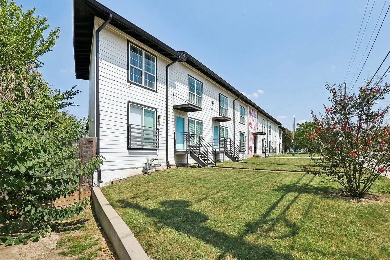 Modern multi-story exterior with horizontal siding, individual balconies with metal railings, and dual-pane windows