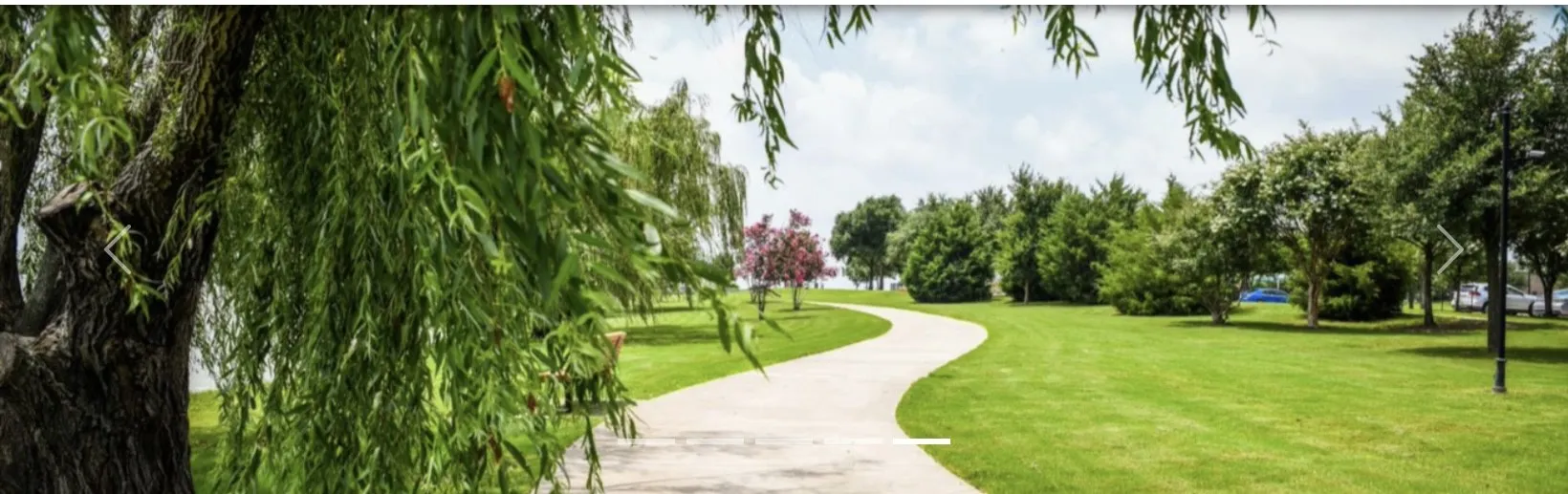 Manicured green space featuring a winding pathway and mature trees