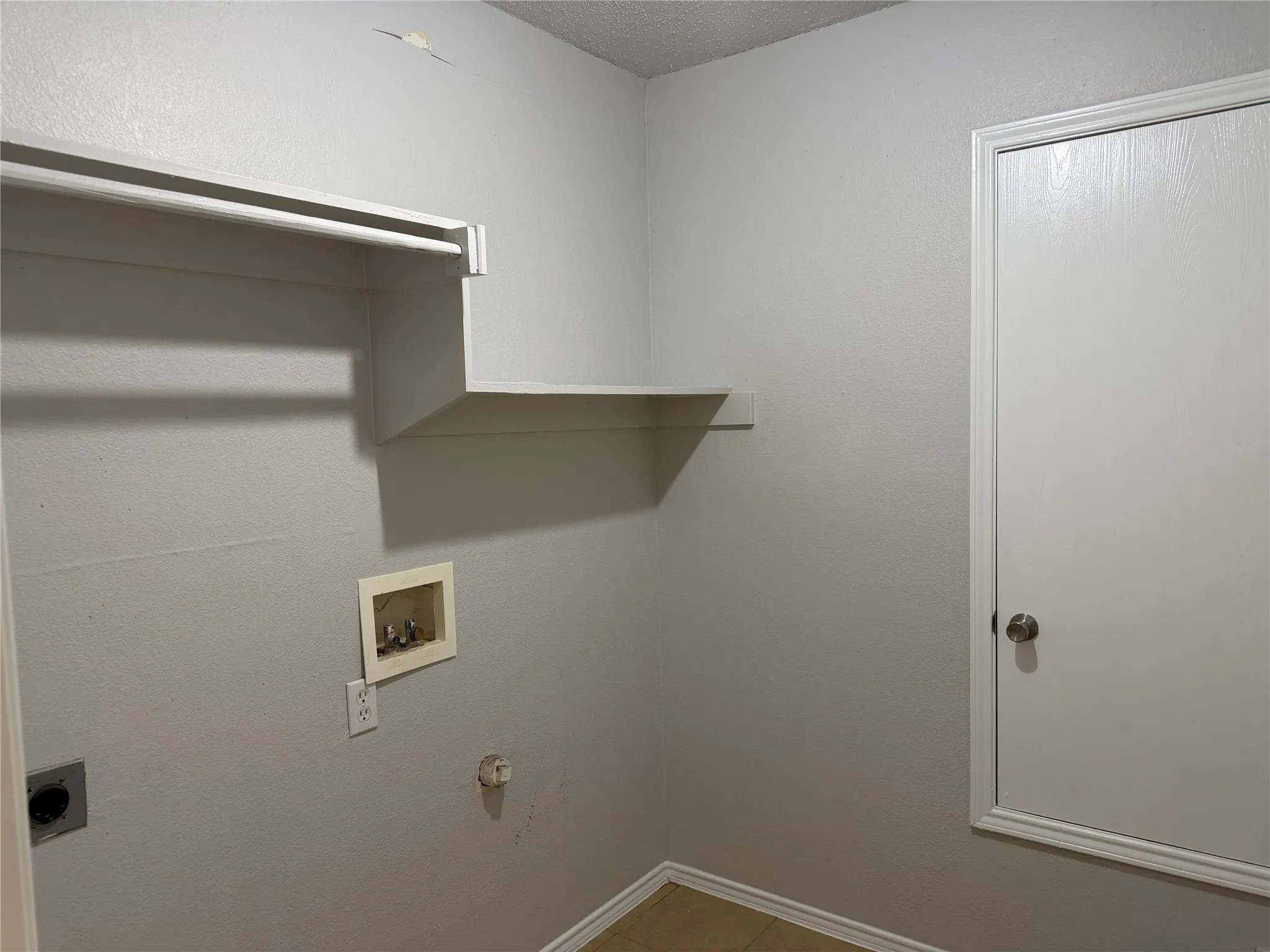 Laundry area featuring built-in shelving, a clothes hanging rod, tile flooring, and utility hookups