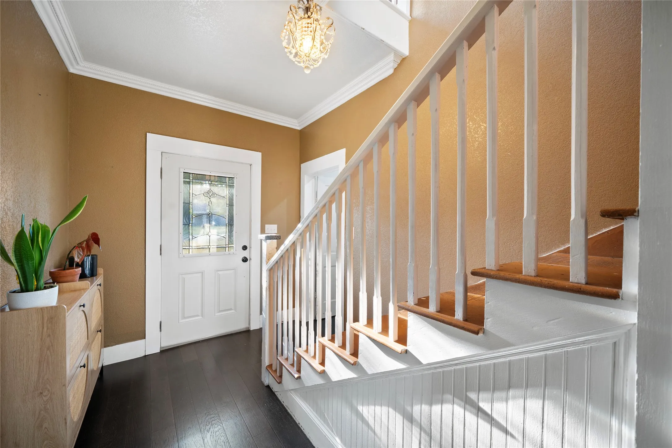 Entryway featuring dark wood-finish flooring, a white paneled door with decorative glass, and a chandelier light fixture