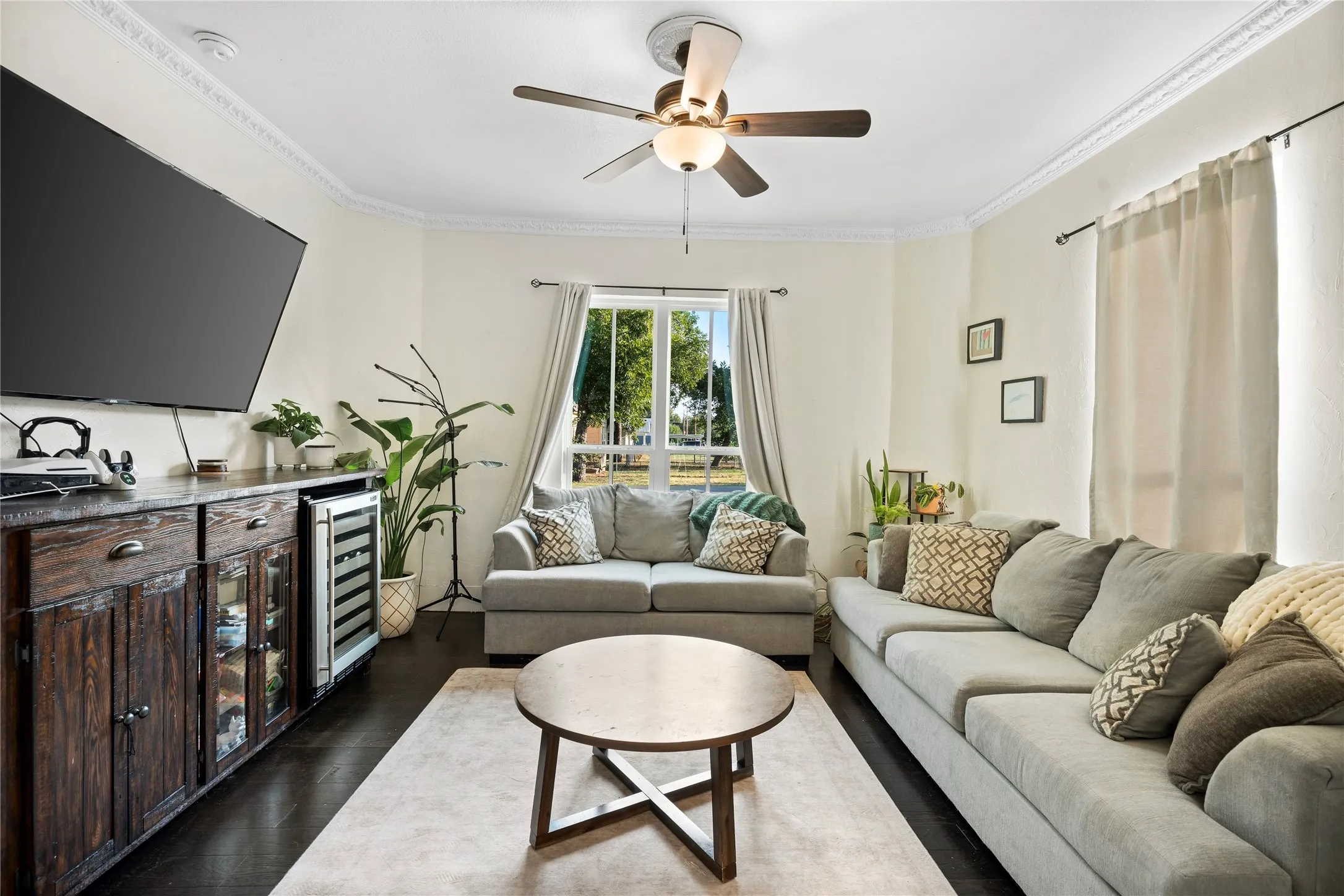 Dark wood-finish flooring with light-toned walls, crown molding, and a ceiling fan with integrated lighting