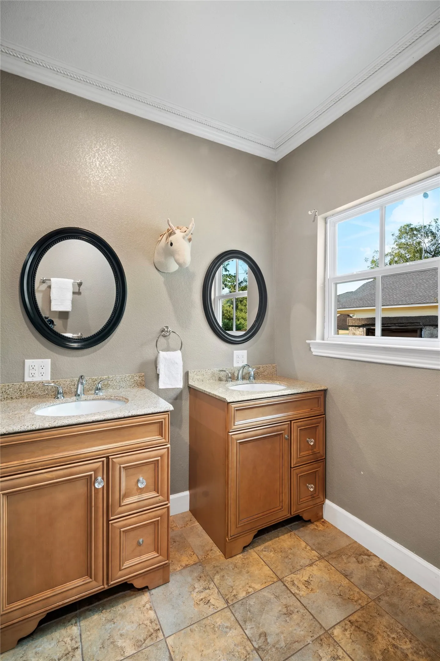 Dual wood-finish vanities with undermount sinks and light-toned countertops