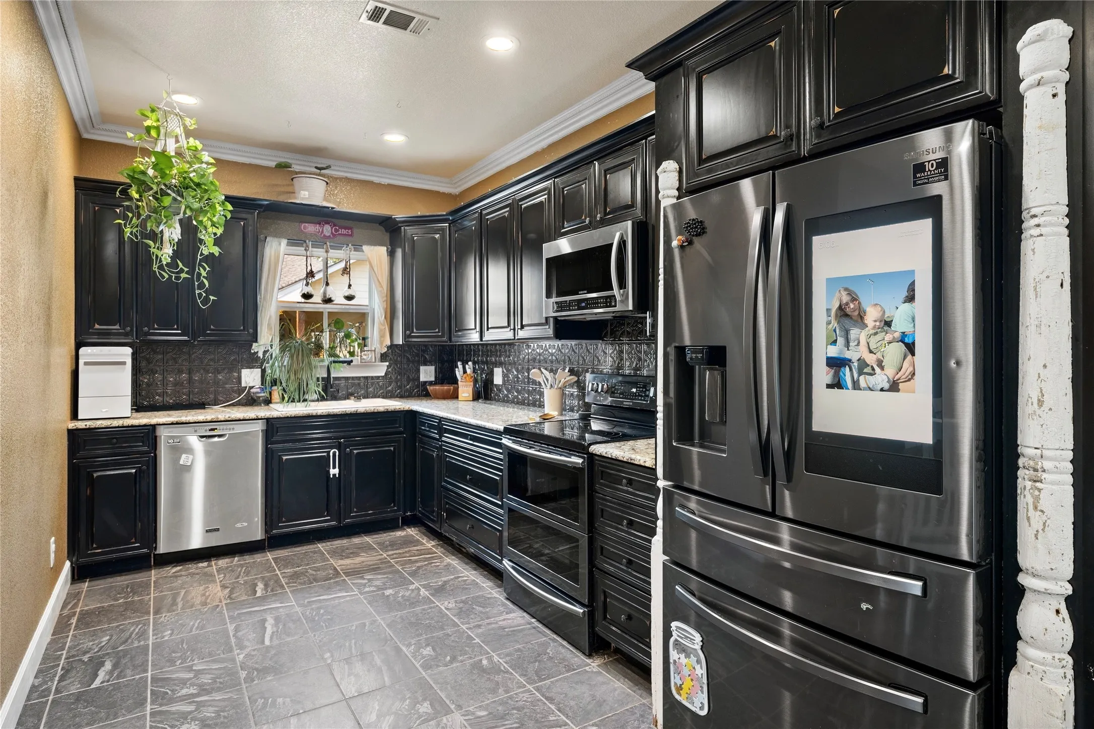Kitchen featuring dark cabinetry, stainless steel appliances, light-toned countertops, and tile flooring