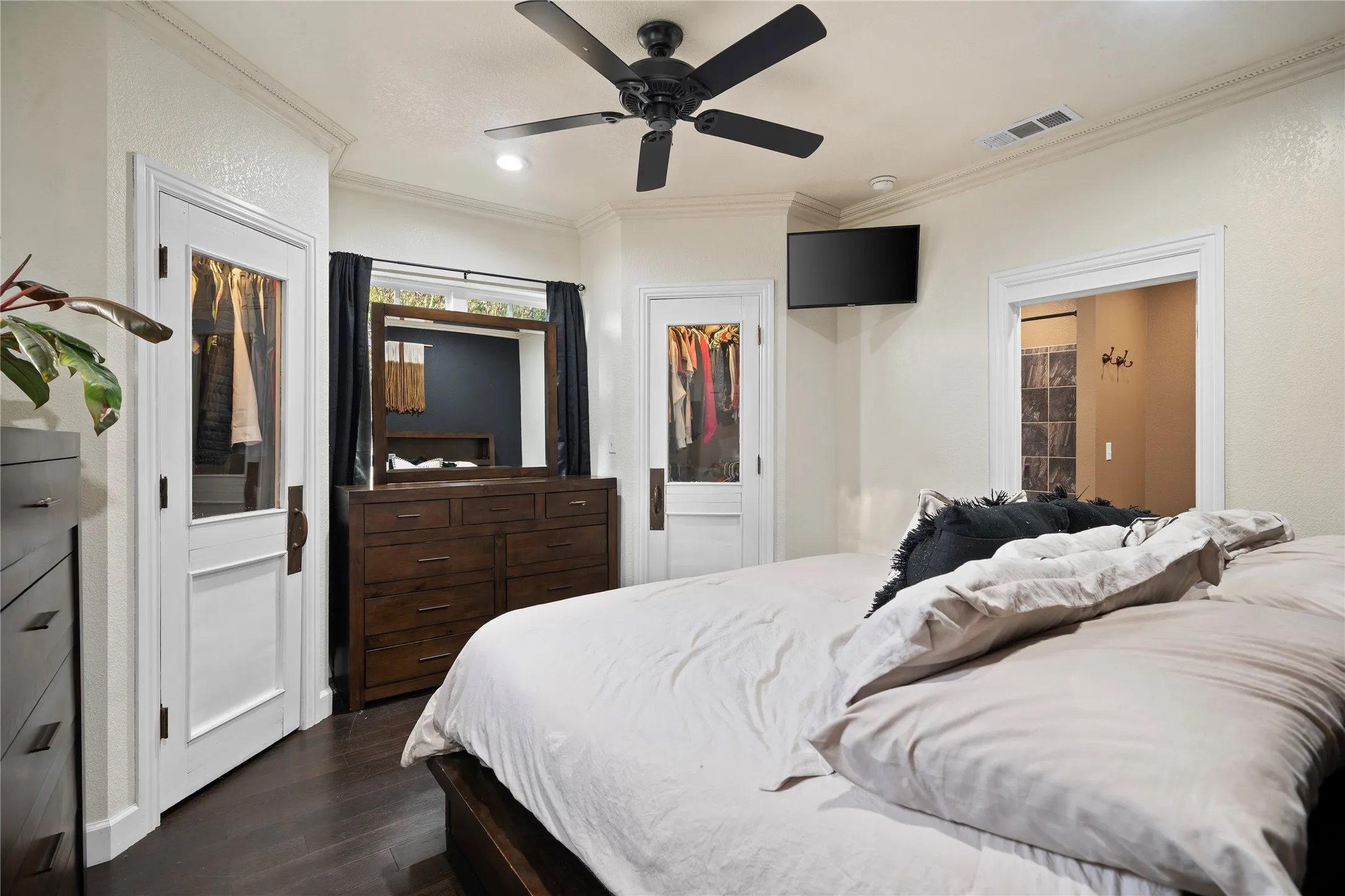 Dark wood-finish flooring, white trim, crown molding, and a ceiling fan with integrated lighting