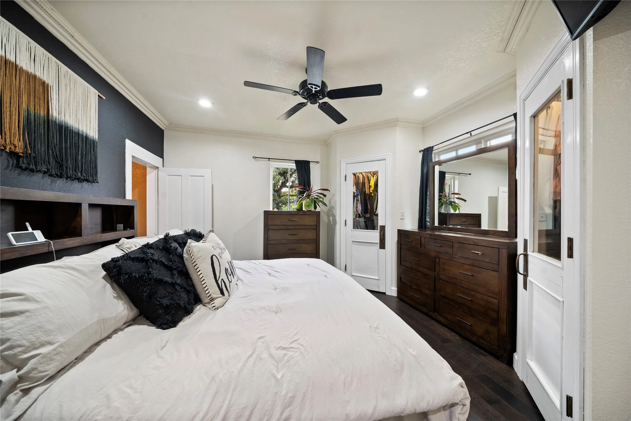 Dark wood-finish flooring, ceiling fan, recessed lighting, crown molding, and white trim accents