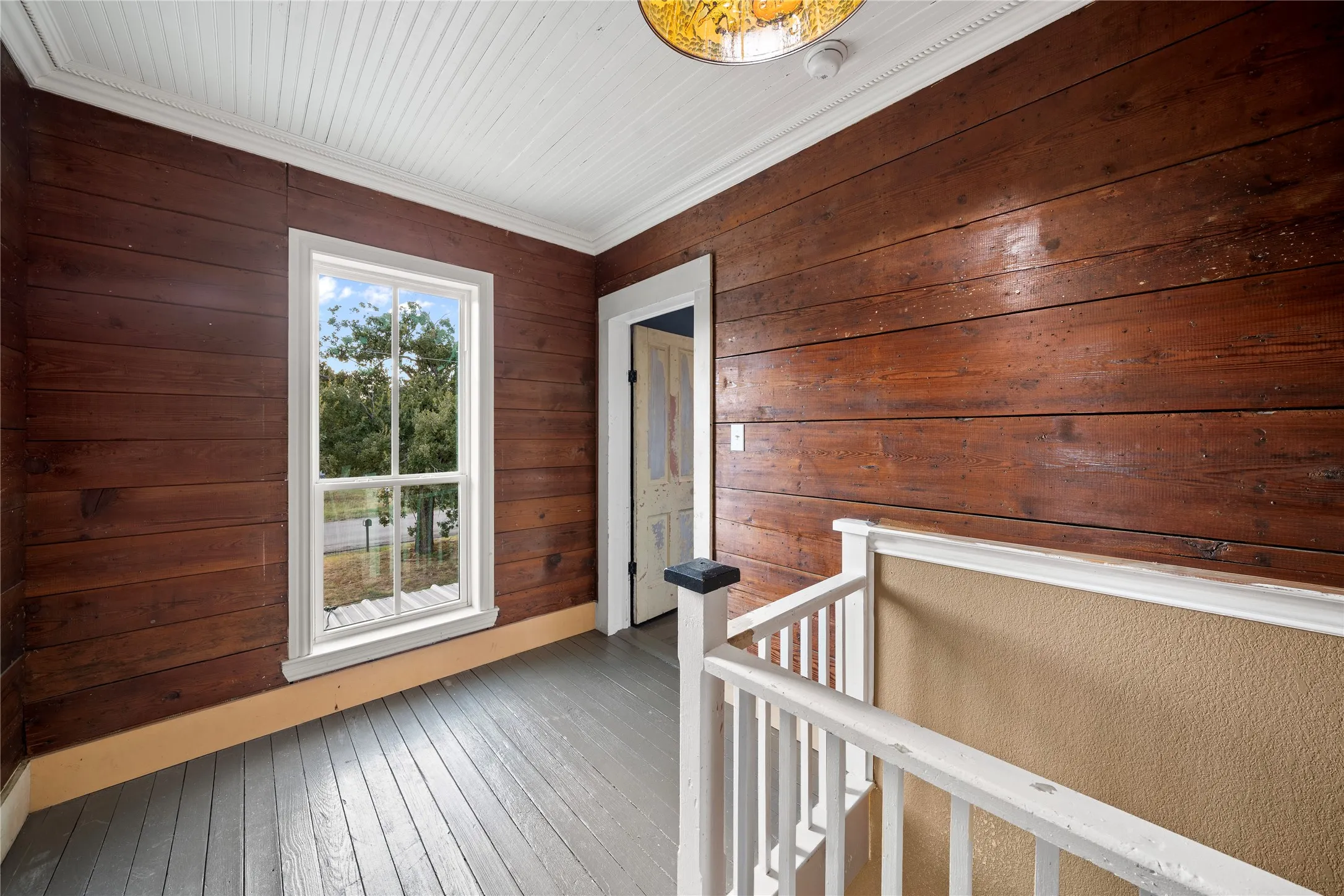 Wood plank walls with a natural finish, white window trim, beadboard ceiling, and painted wood flooring