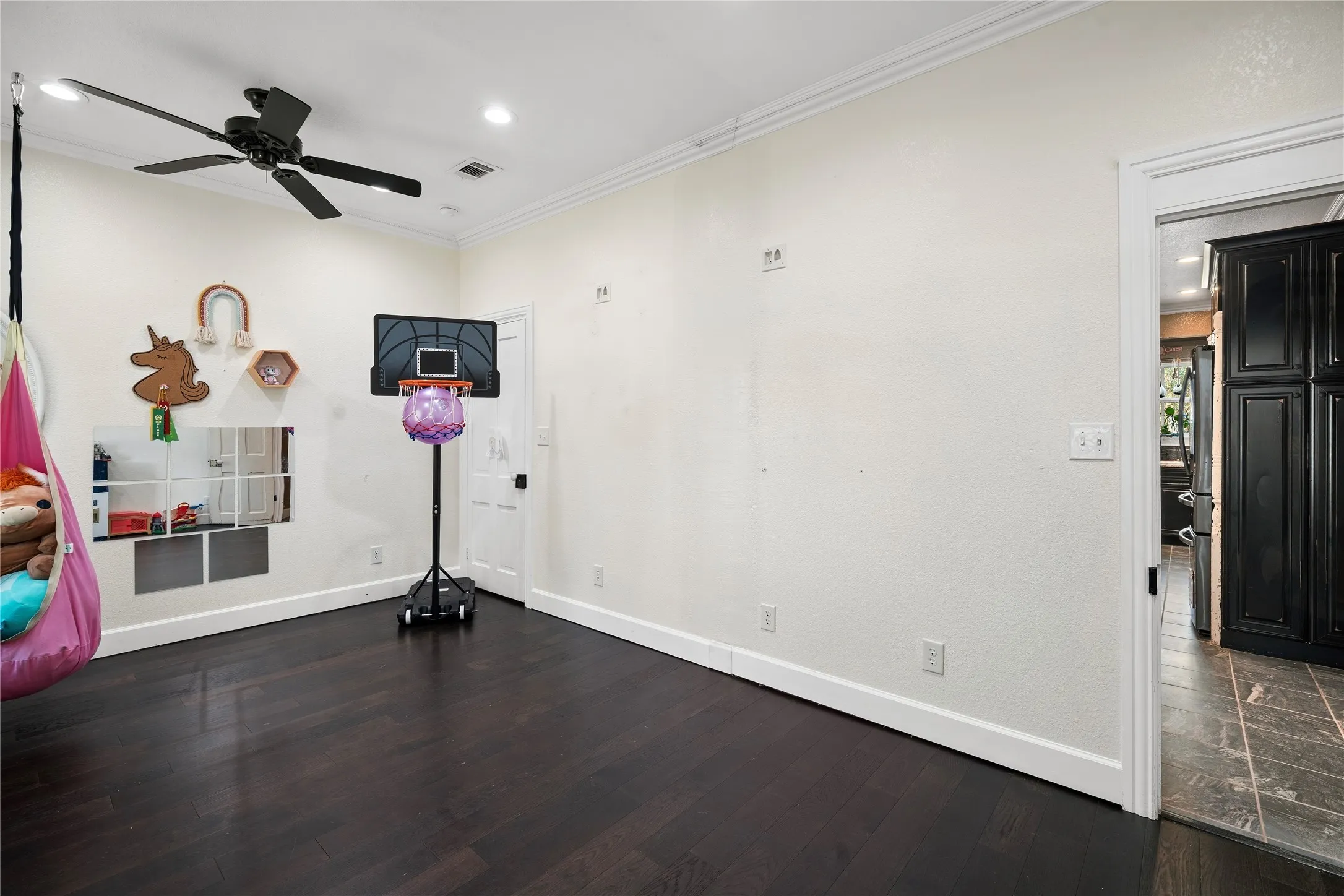 Dark wood-finish flooring with white trim, a black ceiling fan, and recessed lighting