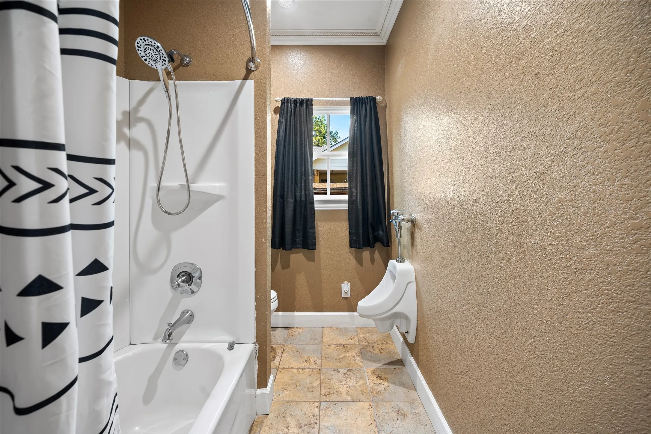 Bathtub with shower fixture, handheld shower head, and tile flooring
