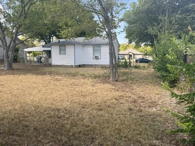 Fenced backyard with mature trees and a covered patio structure