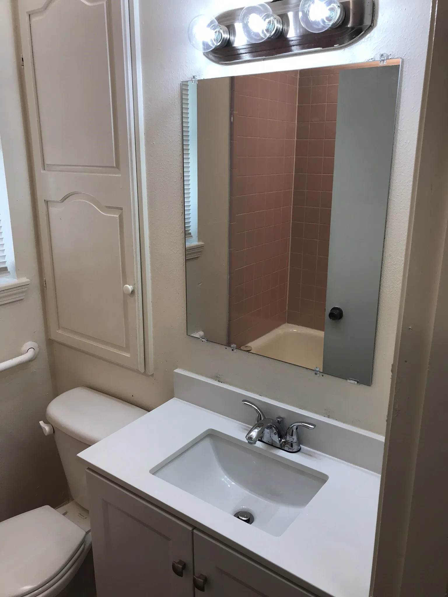 White vanity with an integrated sink, polished chrome faucet, and a wall-mounted mirror
