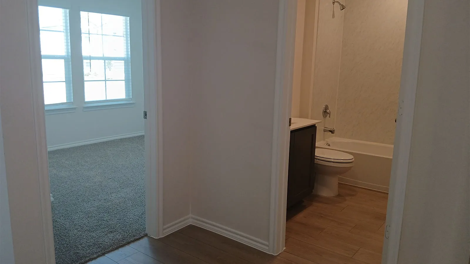 Bathroom featuring a built-in vanity with a white countertop, a white toilet, and a white bathtub with a shower fixture