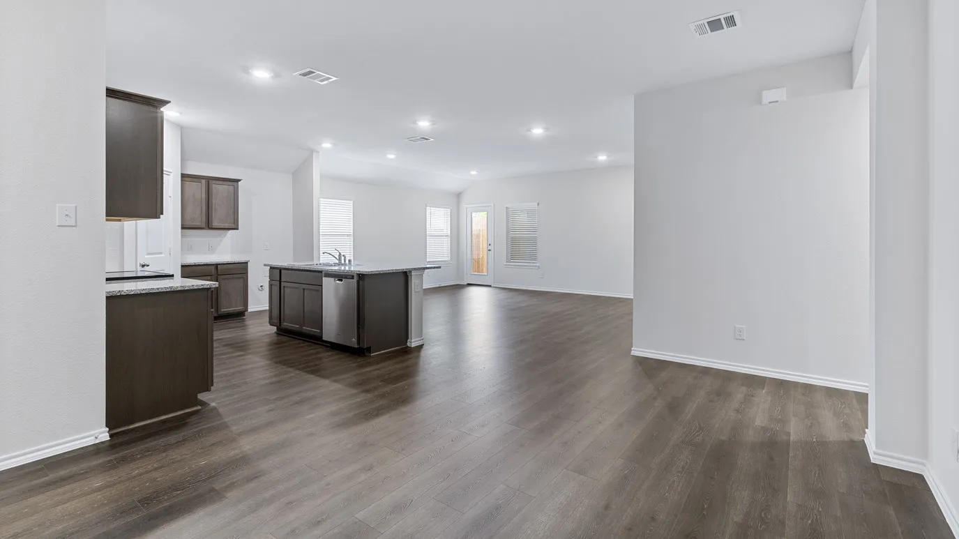 Open-concept living area with wood-finish flooring, recessed lighting, and a kitchen island featuring a stainless steel dishwasher and sink