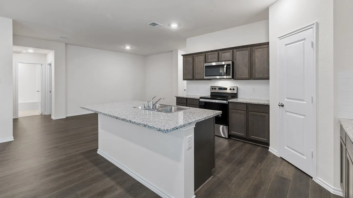 Kitchen featuring a center island, stainless steel appliances, dark wood-finish cabinetry, light-toned countertops, and wood-finish flooring