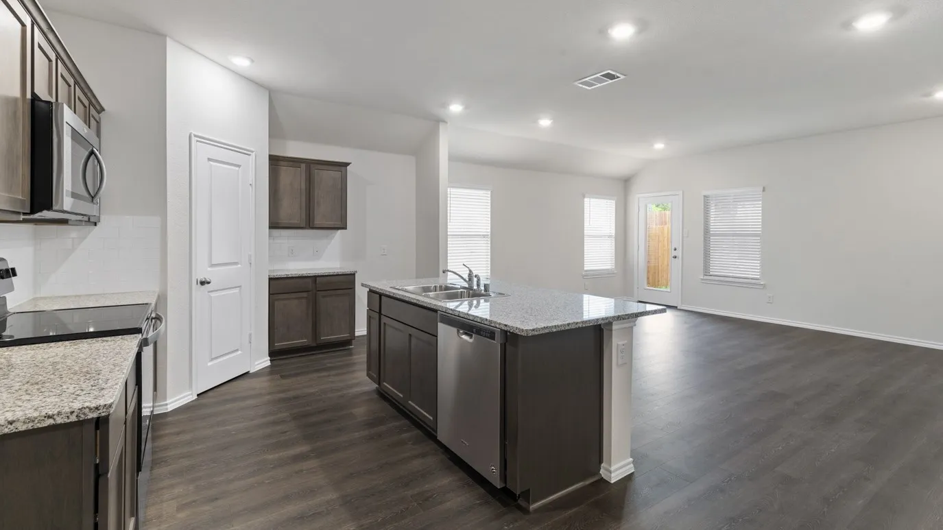 Open-concept kitchen and living area featuring wood-finish flooring, granite countertops, stainless steel appliances, and recessed lighting