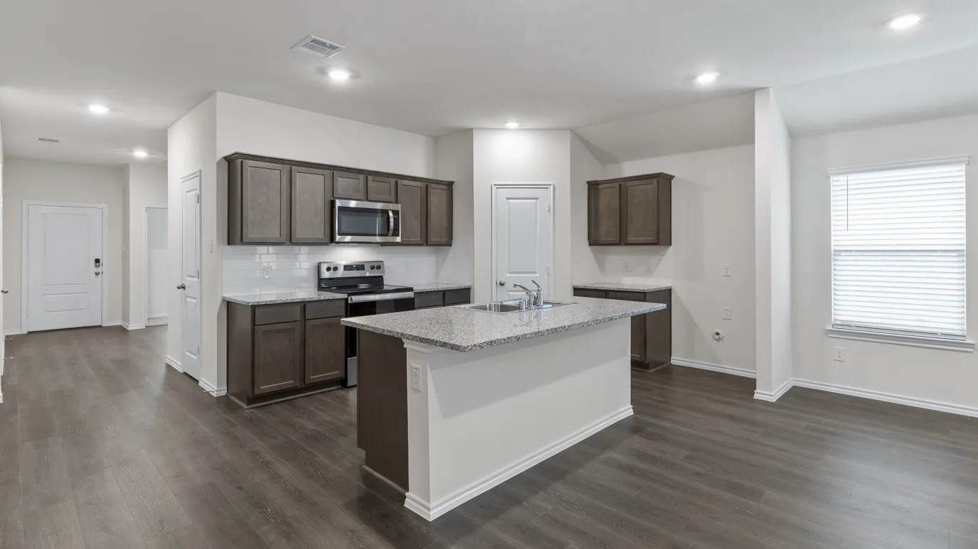Open-concept kitchen with wood-finish flooring, dark wood cabinetry, white subway tile backsplash, and stainless steel appliances