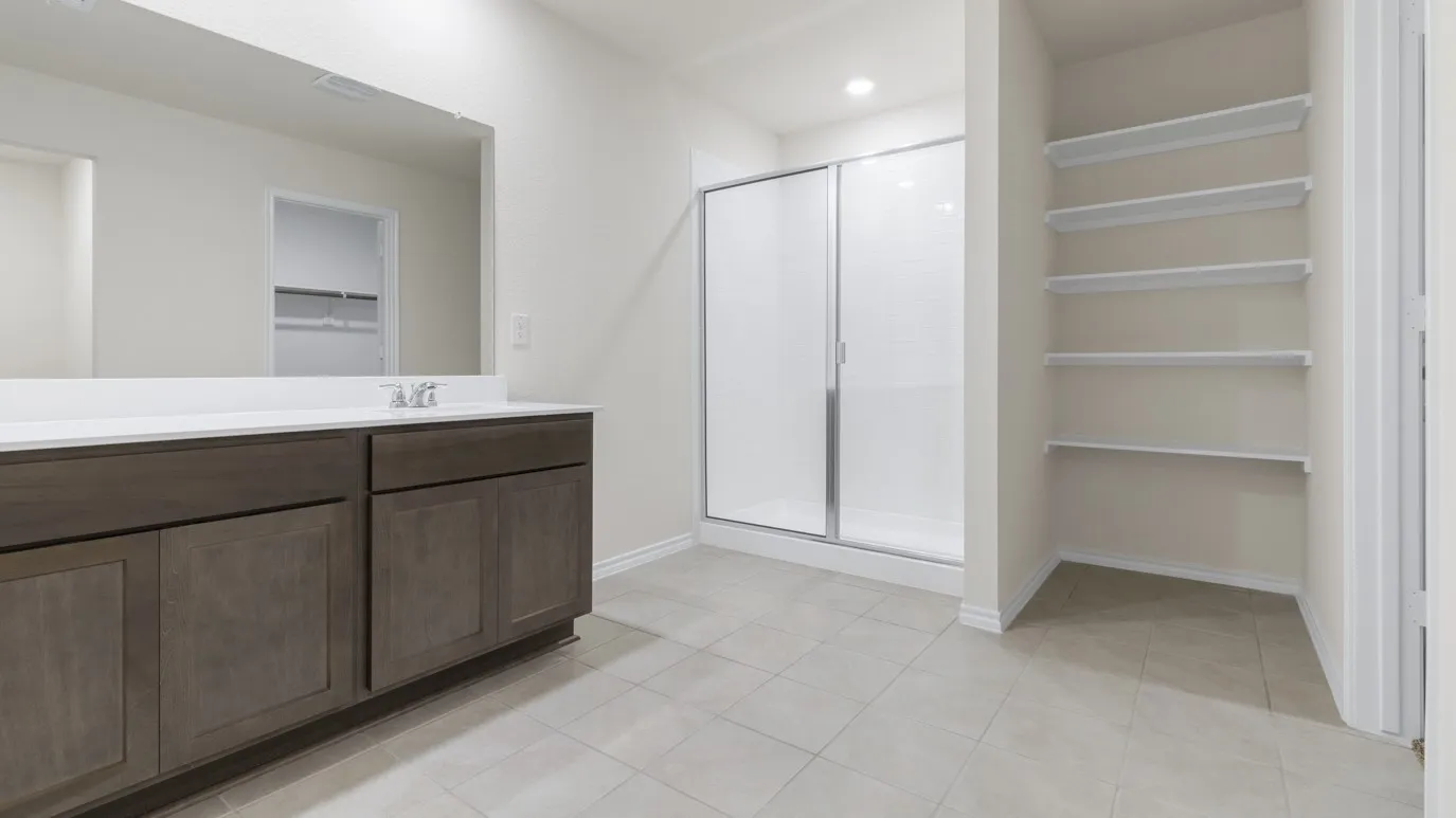 Spacious bathroom featuring a dual-sink vanity with dark wood-finish cabinetry, a large frameless mirror, a glass-enclosed shower, and built-in open shelving