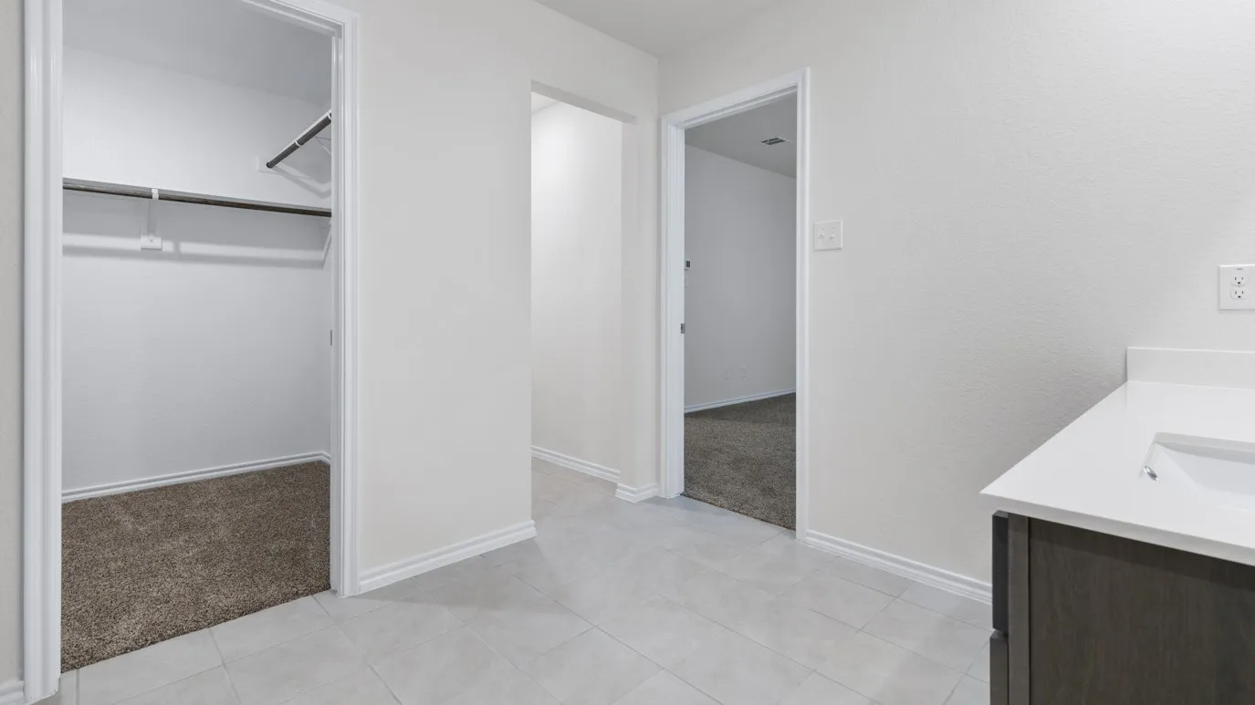 White tile flooring, single vanity with dark wood-finish cabinetry, integrated sink, and white countertop