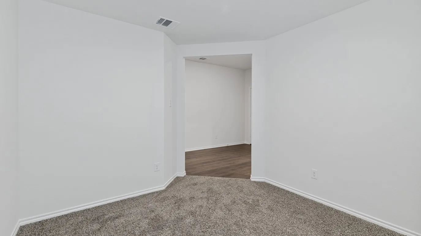 Carpeted room with white walls, leading to an interior space with wood-finish flooring