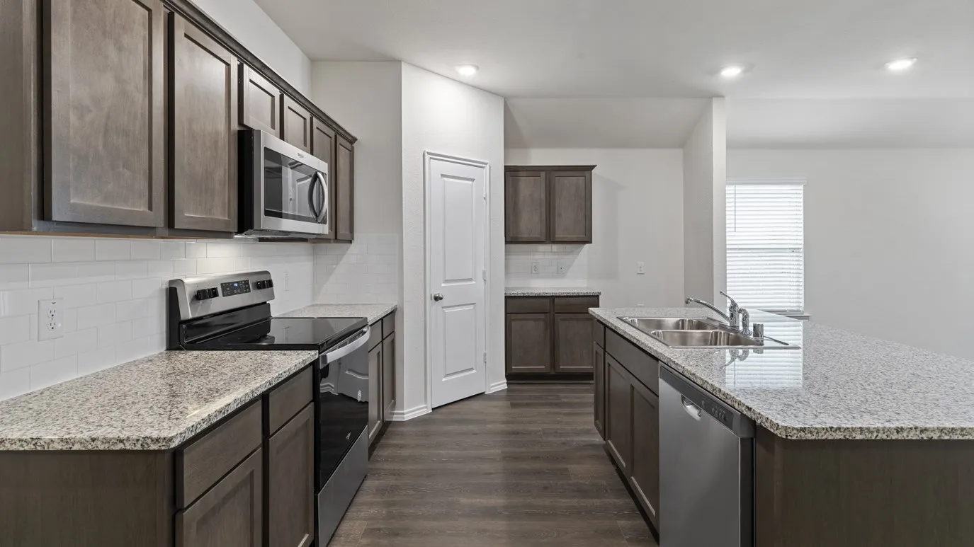 Kitchen featuring dark wood-finish cabinetry, light speckled countertops, a white subway tile backsplash, stainless steel appliances, and wood-finish flooring