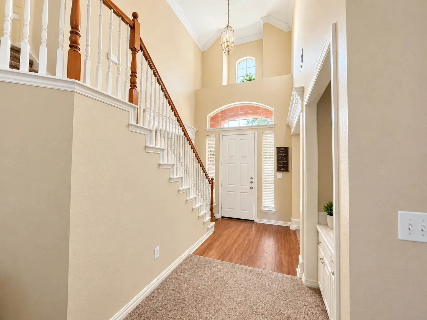 Two-story foyer with a vaulted ceiling, wood-finish flooring, and a white paneled entry door with sidelights