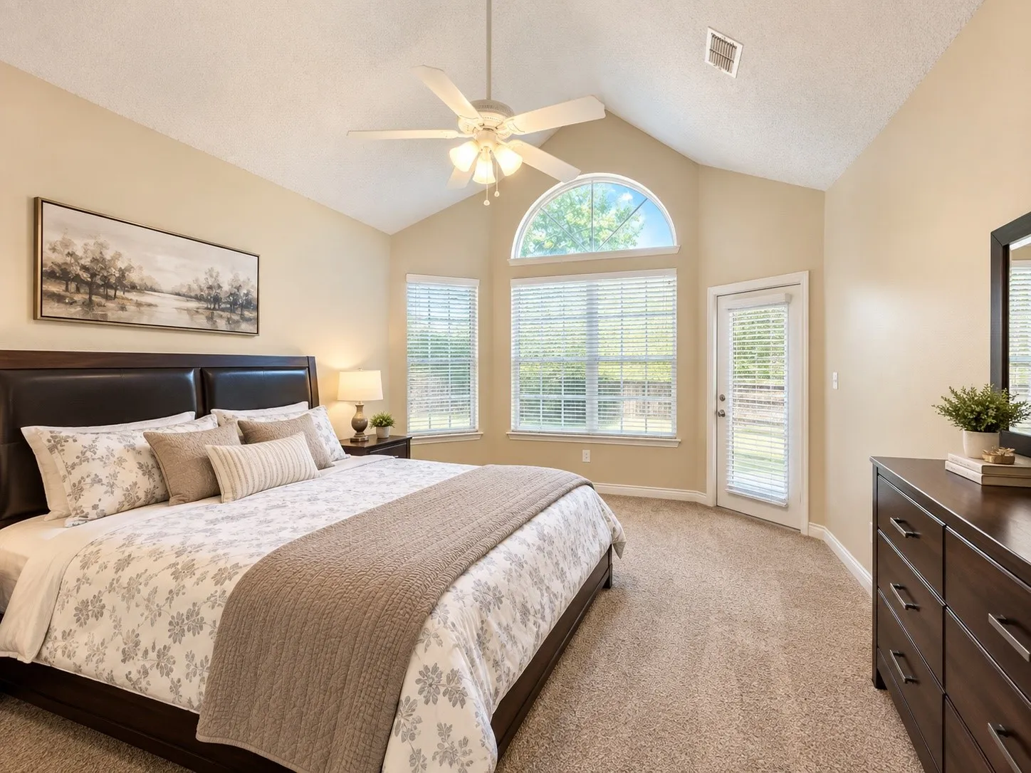 Vaulted ceiling with ceiling fan, arched transom window, glass-paned exterior door, and carpet flooring