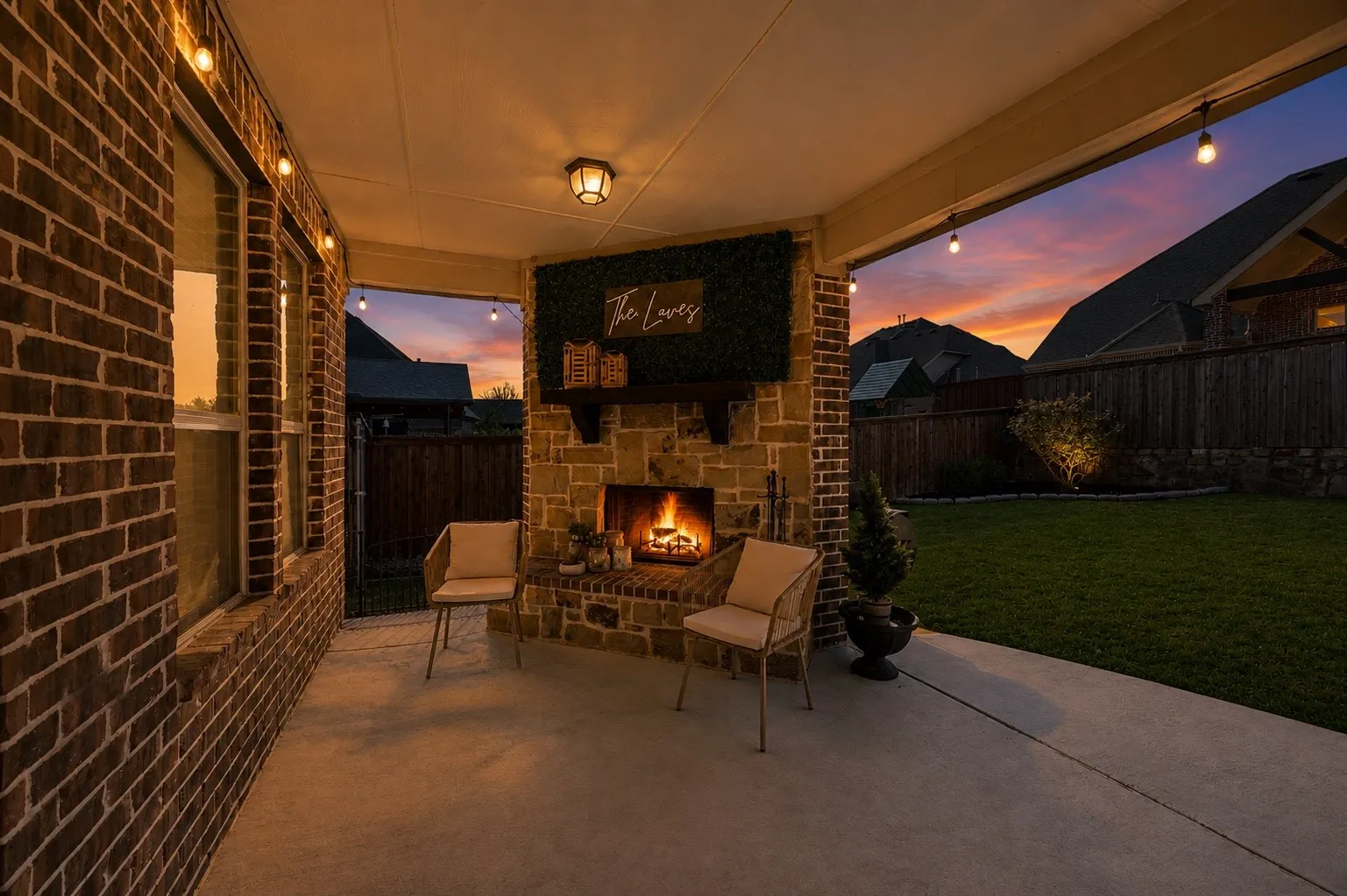 Covered patio with a stone and brick fireplace, overhead lighting, and a concrete surface