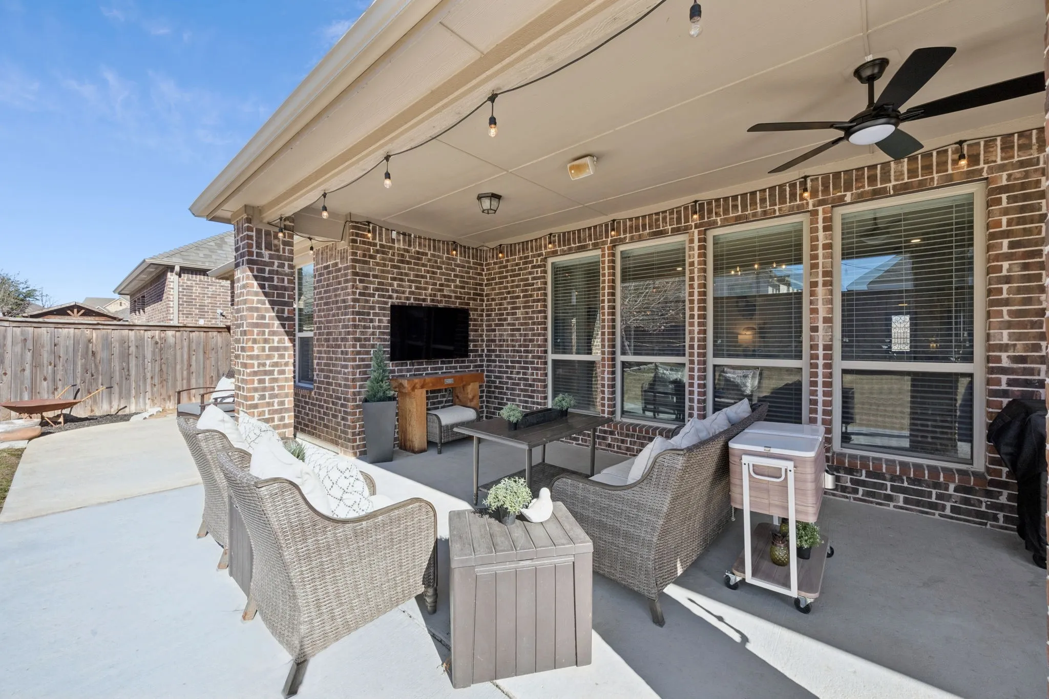 Covered patio with a brick exterior, concrete flooring, and an exterior ceiling fan