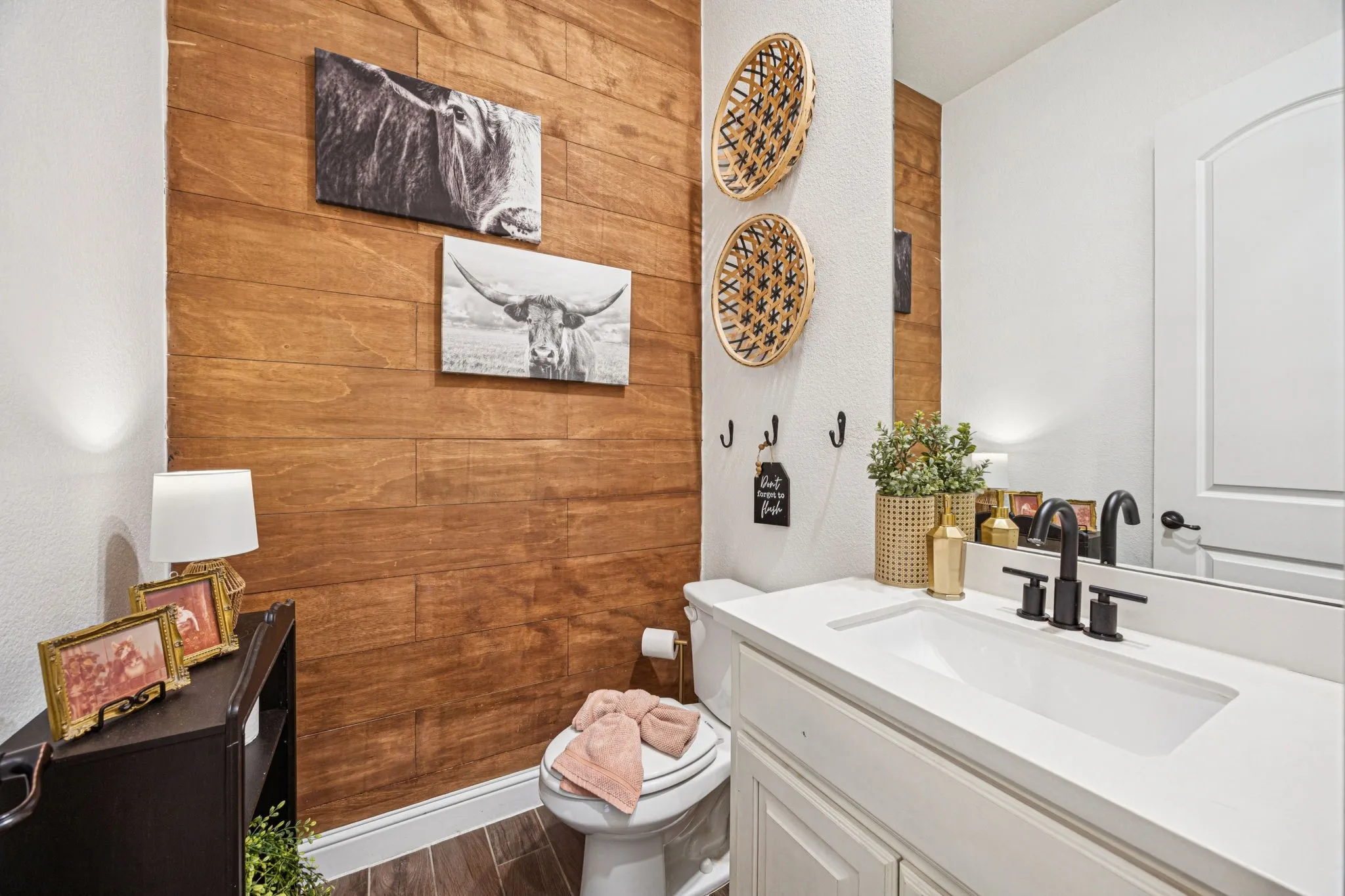 Wood-finish accent wall, built-in vanity with integrated sink, sleek black faucet, and a large wall-mounted mirror