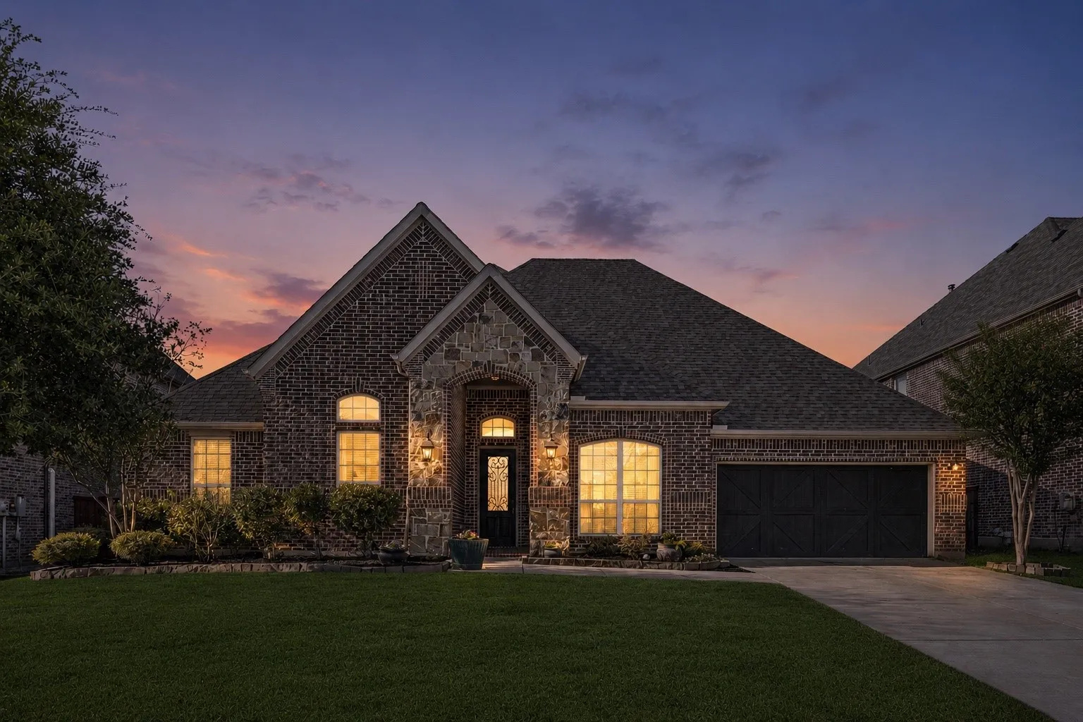 Brick and stone exterior with an arched entryway, gabled roofline, and attached garage