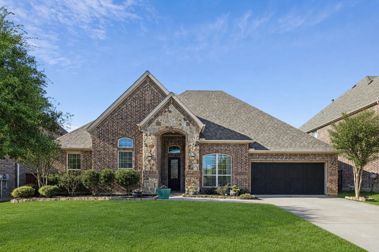 Brick and stone exterior with gabled roofline, arched entry, and a two-car garage