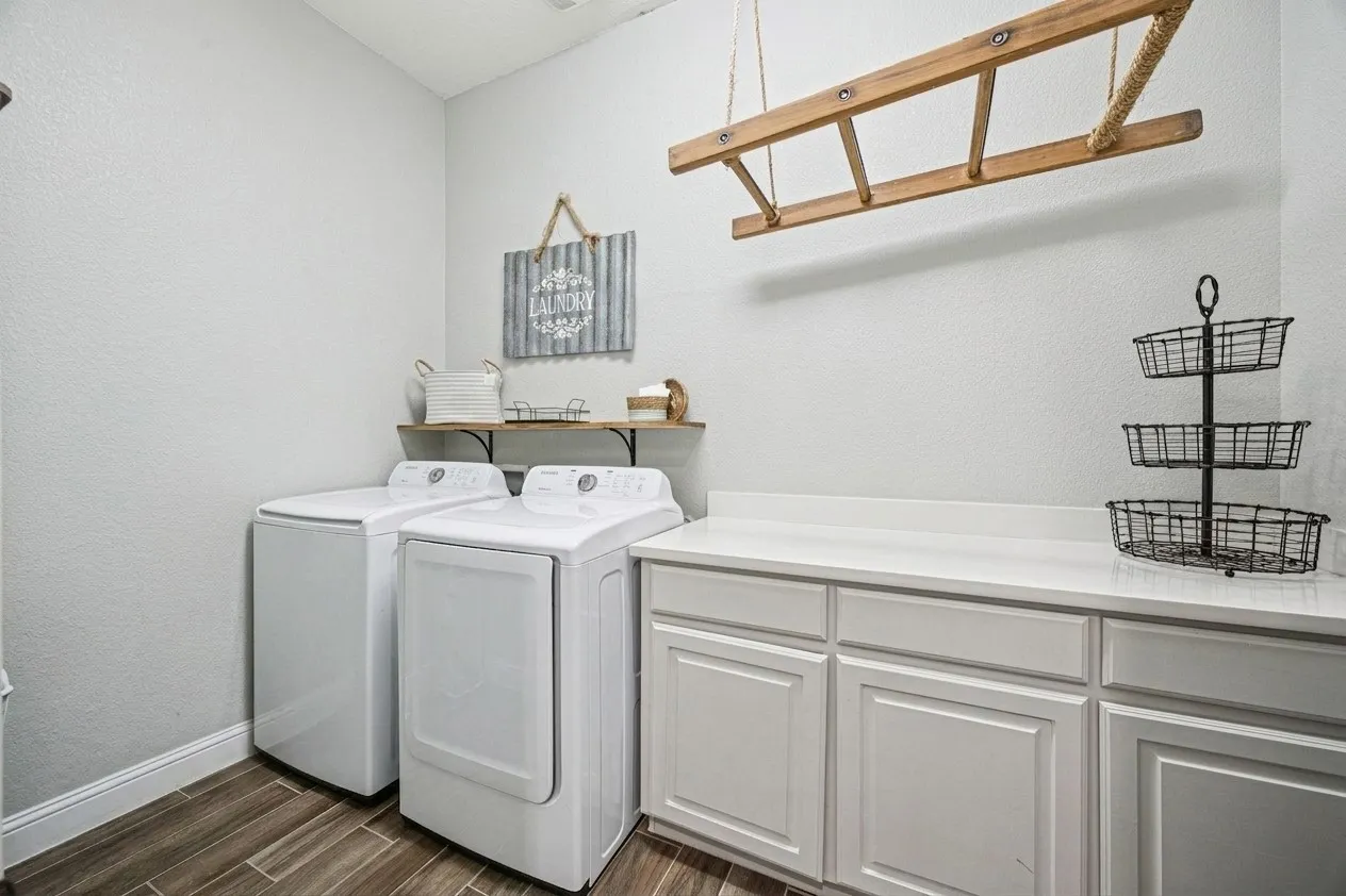 Laundry area featuring wood-finish flooring, white cabinetry, and a white countertop